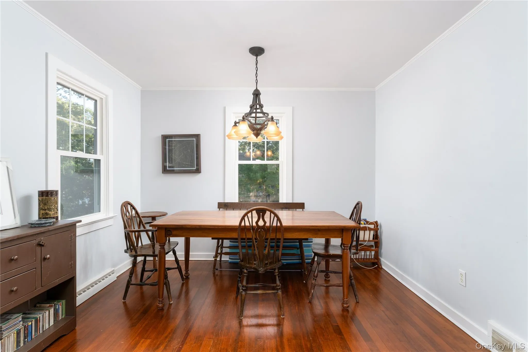 Dining space featuring ornamental molding, baseboard heating, and dark wood-style floors Dining space featuring ornamental molding, baseboard heating, and dark wood-style floors