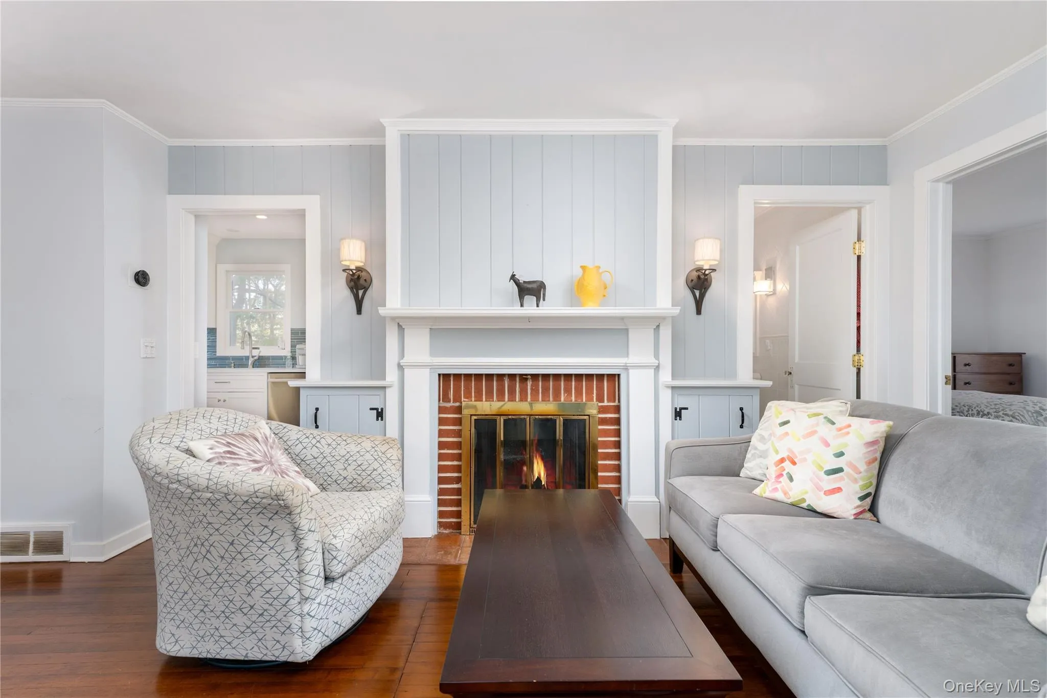 Living room with crown molding, a brick fireplace, and wood finished floors Living room with crown molding, a brick fireplace, and wood finished floors