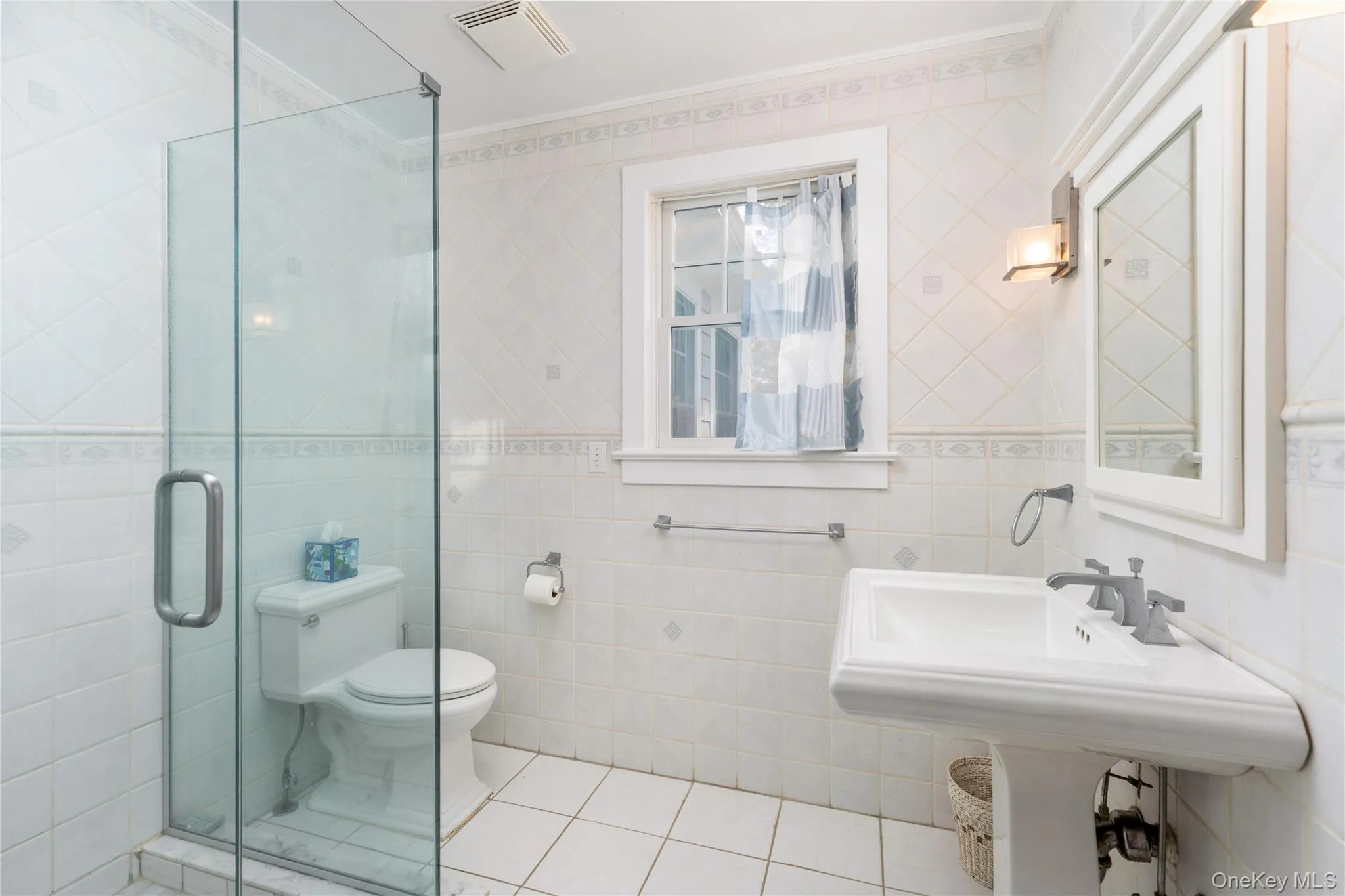 Bathroom with light tile patterned floors, crown molding, tile walls, and a shower stall Bathroom with light tile patterned floors, crown molding, tile walls, and a shower stall