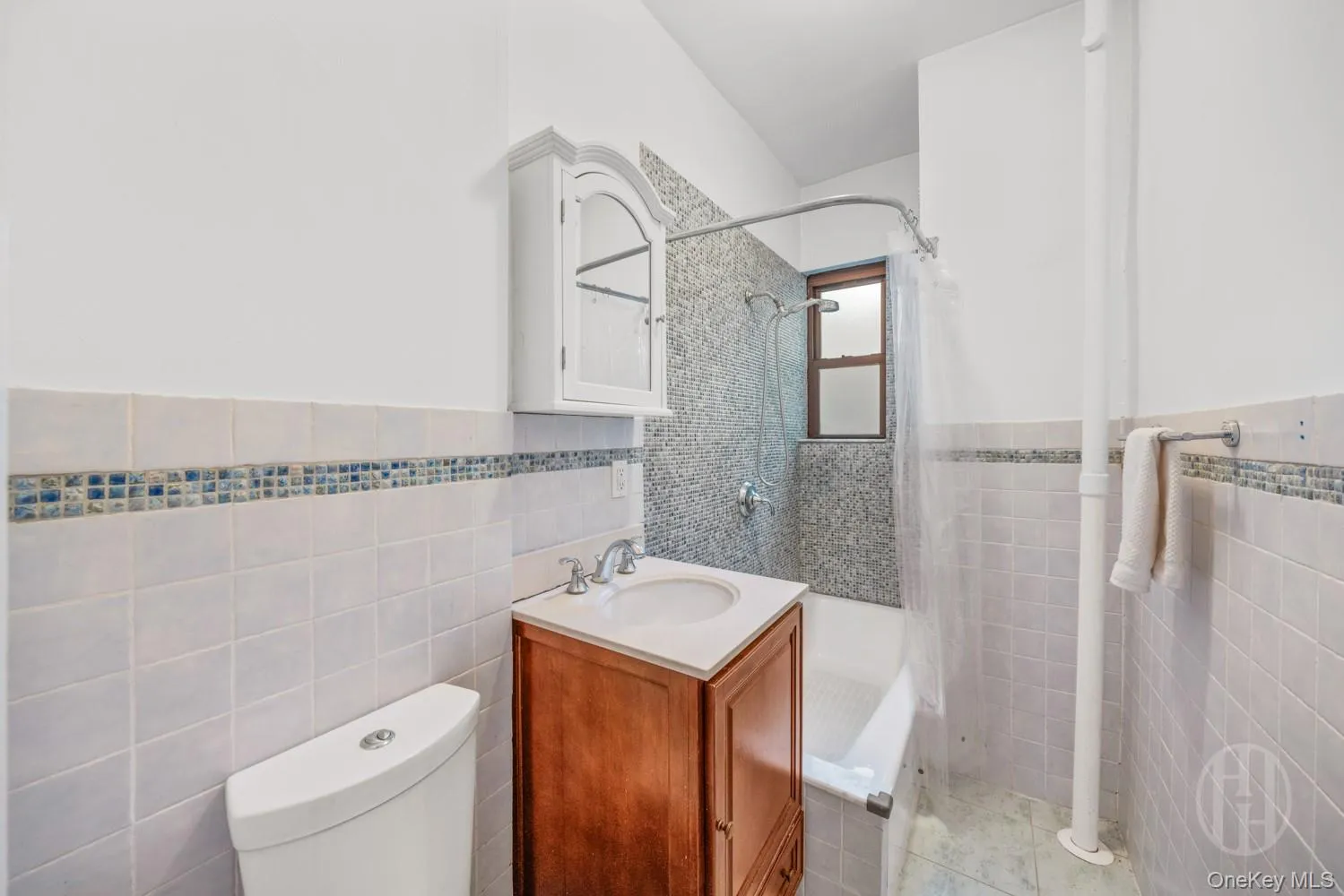 Full bathroom featuring tile walls, wainscoting, vanity, tiled shower / bath, and light tile patterned floors Full bathroom featuring tile walls, wainscoting, vanity, tiled shower / bath, and light tile patterned floors