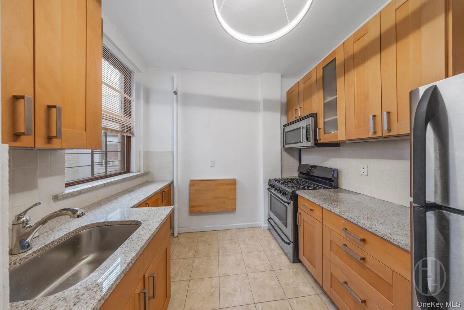 Kitchen with stainless steel appliances, glass insert cabinets, light stone counters, and decorative backsplash Kitchen with stainless steel appliances, glass insert cabinets, light stone counters, and decorative backsplash