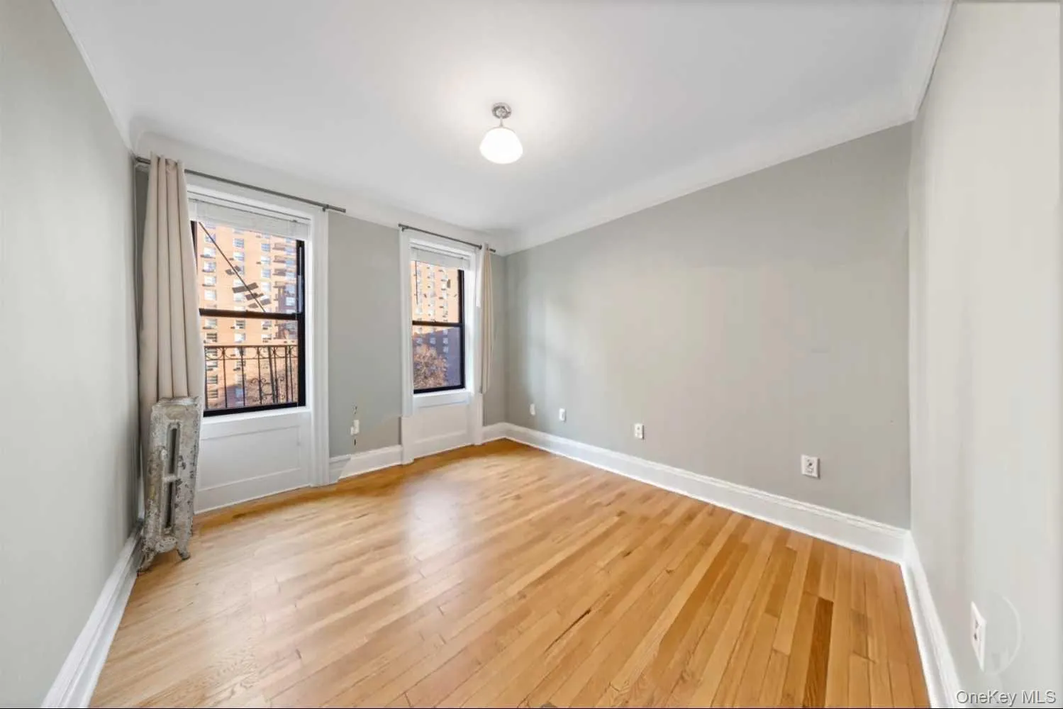 Unfurnished room (1/2) with light wood finished floors and radiator heating unit Unfurnished room (1/2) with light wood finished floors and radiator heating unit