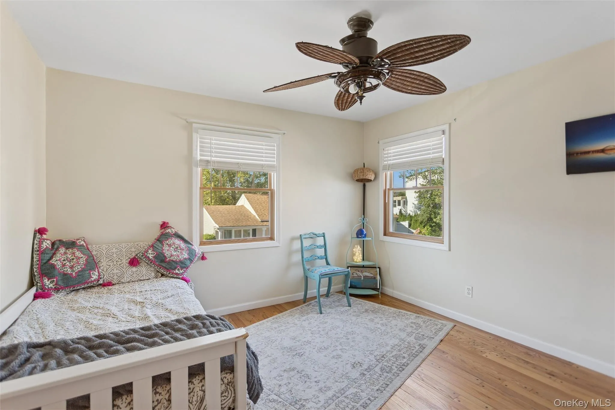 Bedroom featuring light wood-type flooring, multiple windows, and a ceiling fan Bedroom featuring light wood-type flooring, multiple windows, and a ceiling fan