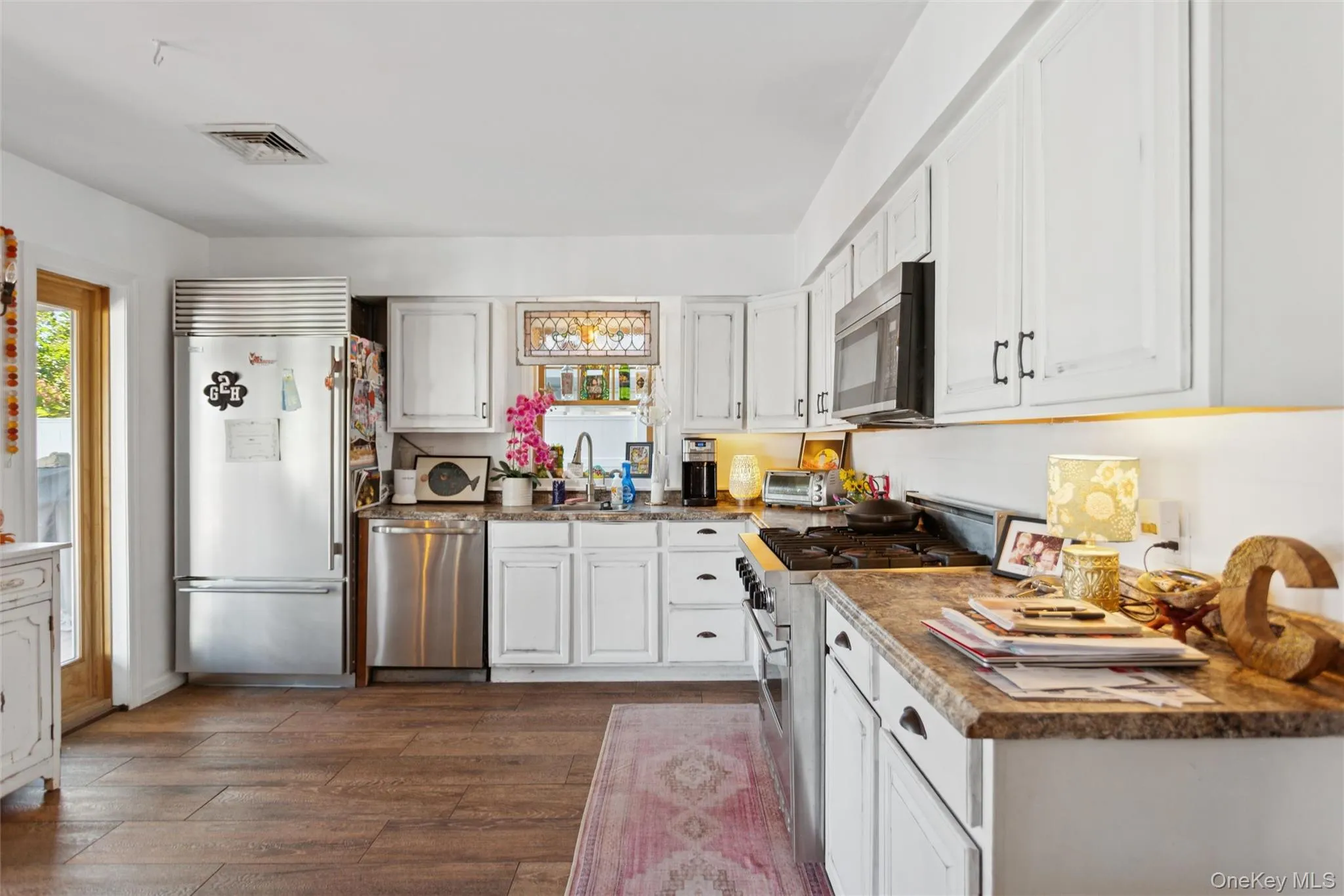 Kitchen with premium appliances, white cabinets, dark wood-style flooring, and dark countertops Kitchen with premium appliances, white cabinets, dark wood-style flooring, and dark countertops