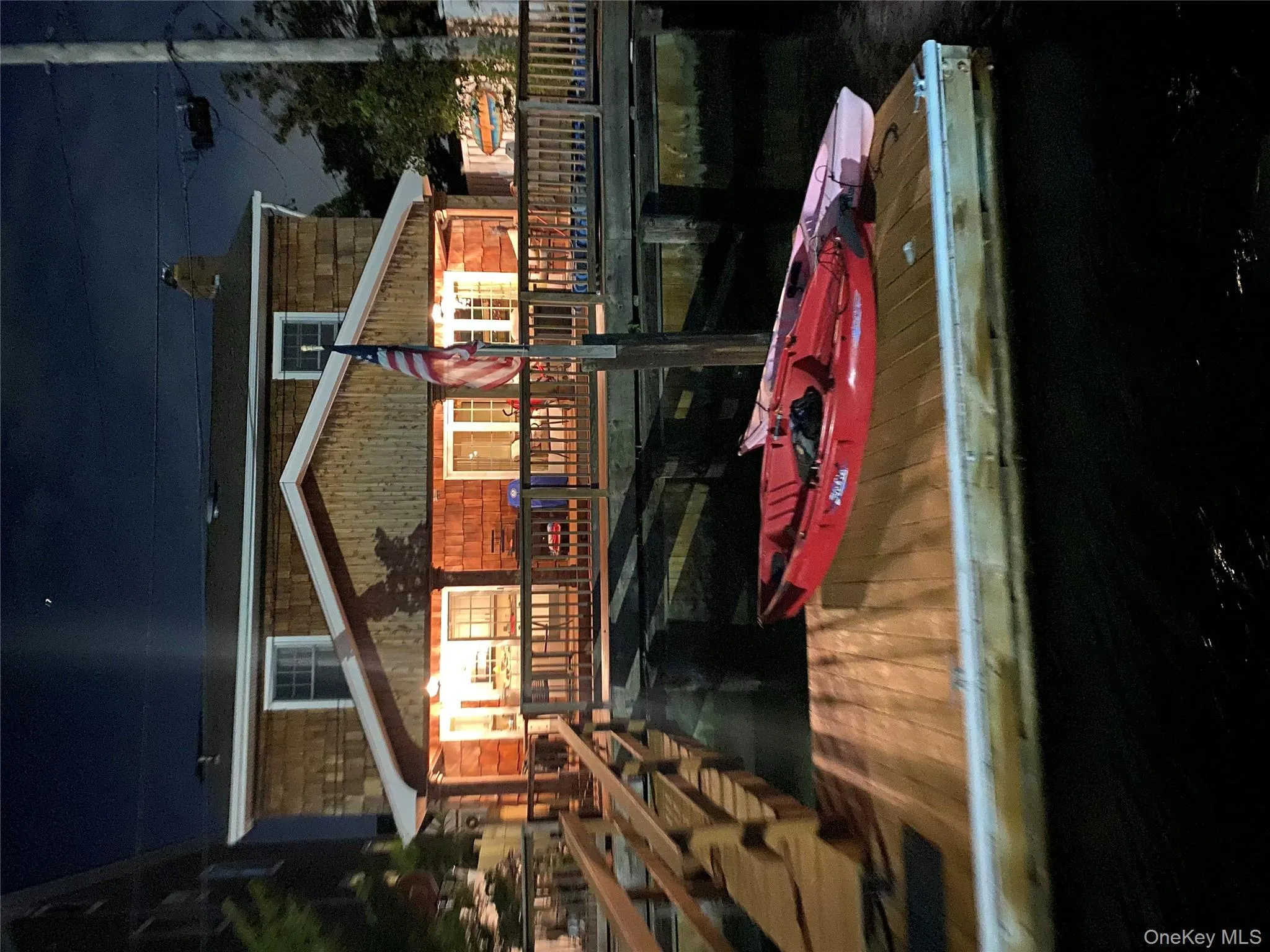 Back of house at night featuring a wooden deck and a chimney Back of house at night featuring a wooden deck and a chimney