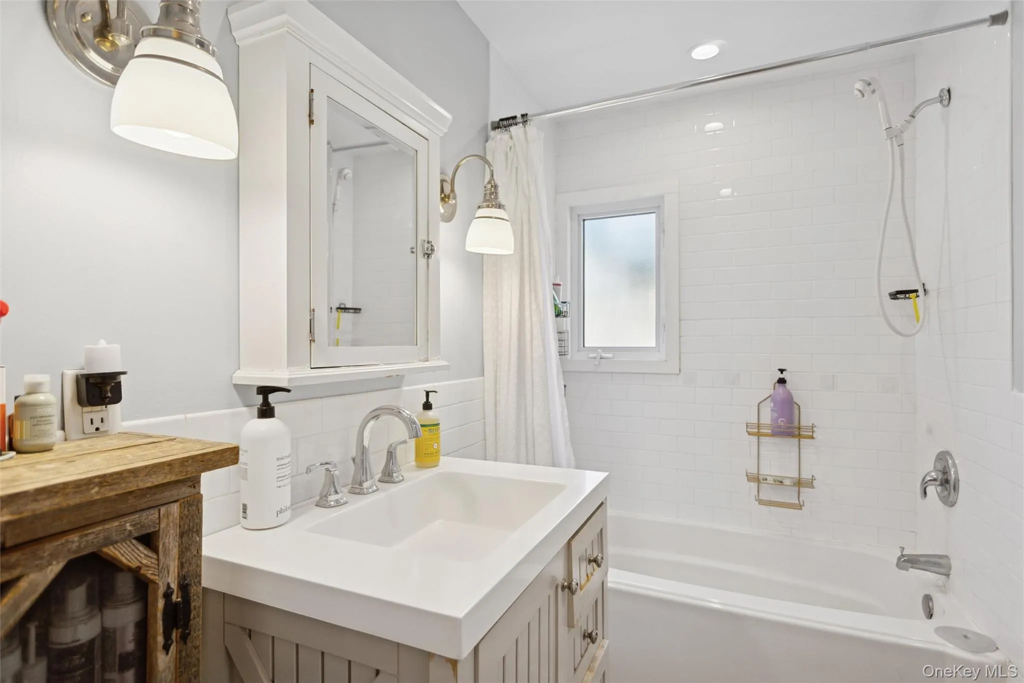 Bathroom featuring vanity, shower / tub combo, tile walls, and backsplash Bathroom featuring vanity, shower / tub combo, tile walls, and backsplash