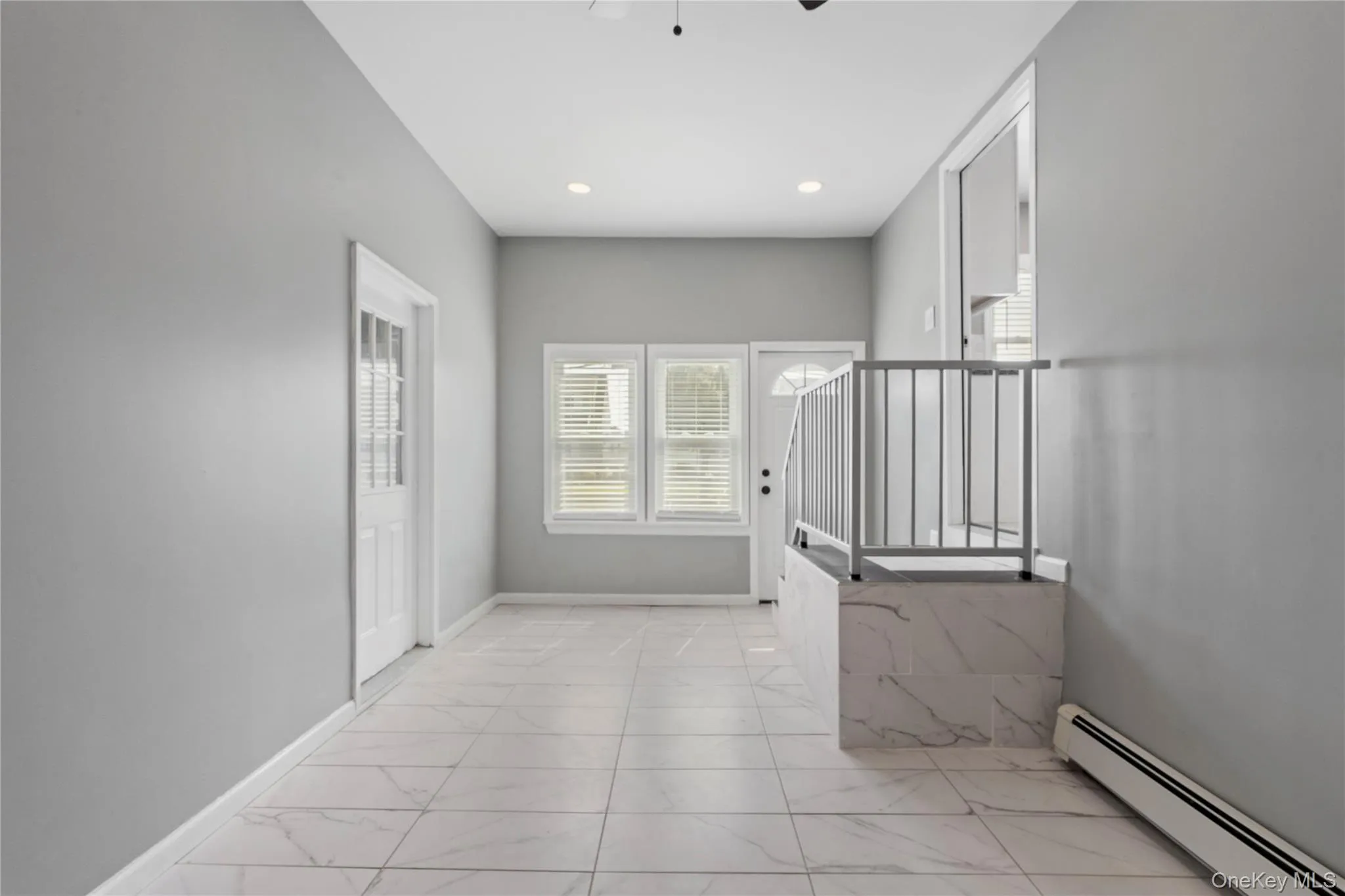 Corridor featuring a baseboard heating unit, light marble finish flooring, and recessed lighting Corridor featuring a baseboard heating unit, light marble finish flooring, and recessed lighting
