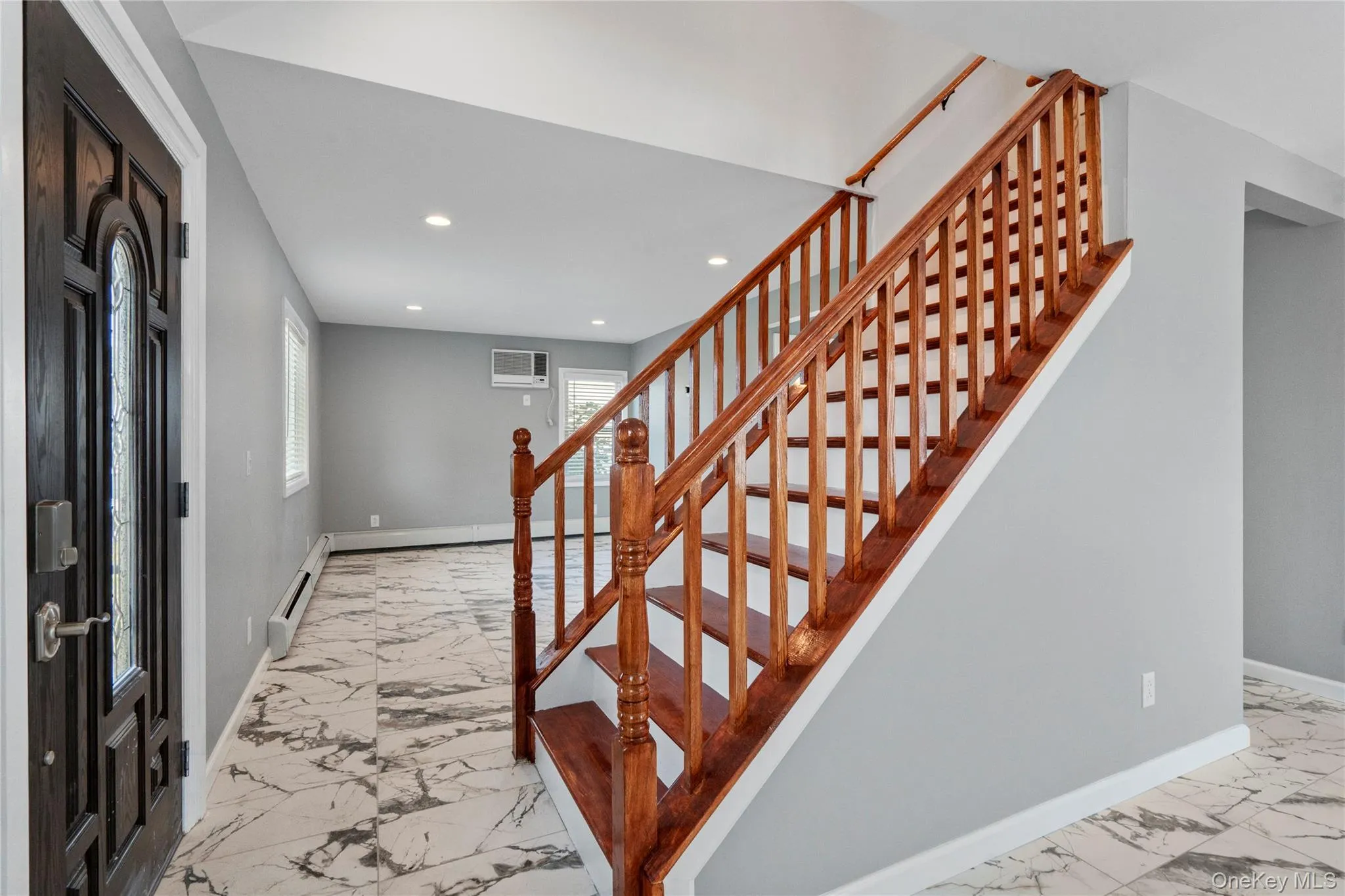 Foyer entrance featuring light marble finish flooring, stairs, recessed lighting, and a baseboard heating unit Foyer entrance featuring light marble finish flooring, stairs, recessed lighting, and a baseboard heating unit