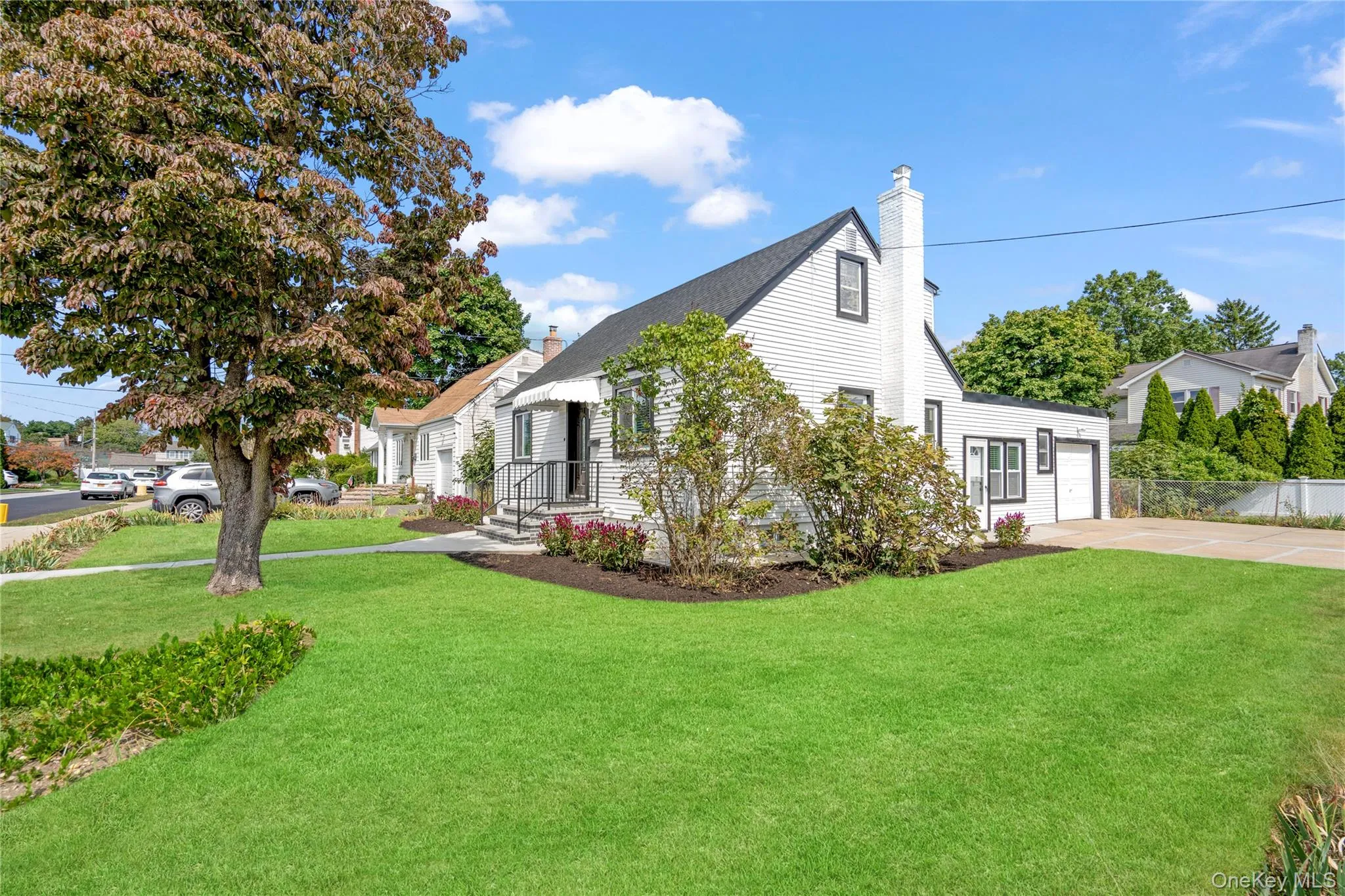 View of front of home with concrete driveway, a chimney, and an attached garage View of front of home with concrete driveway, a chimney, and an attached garage