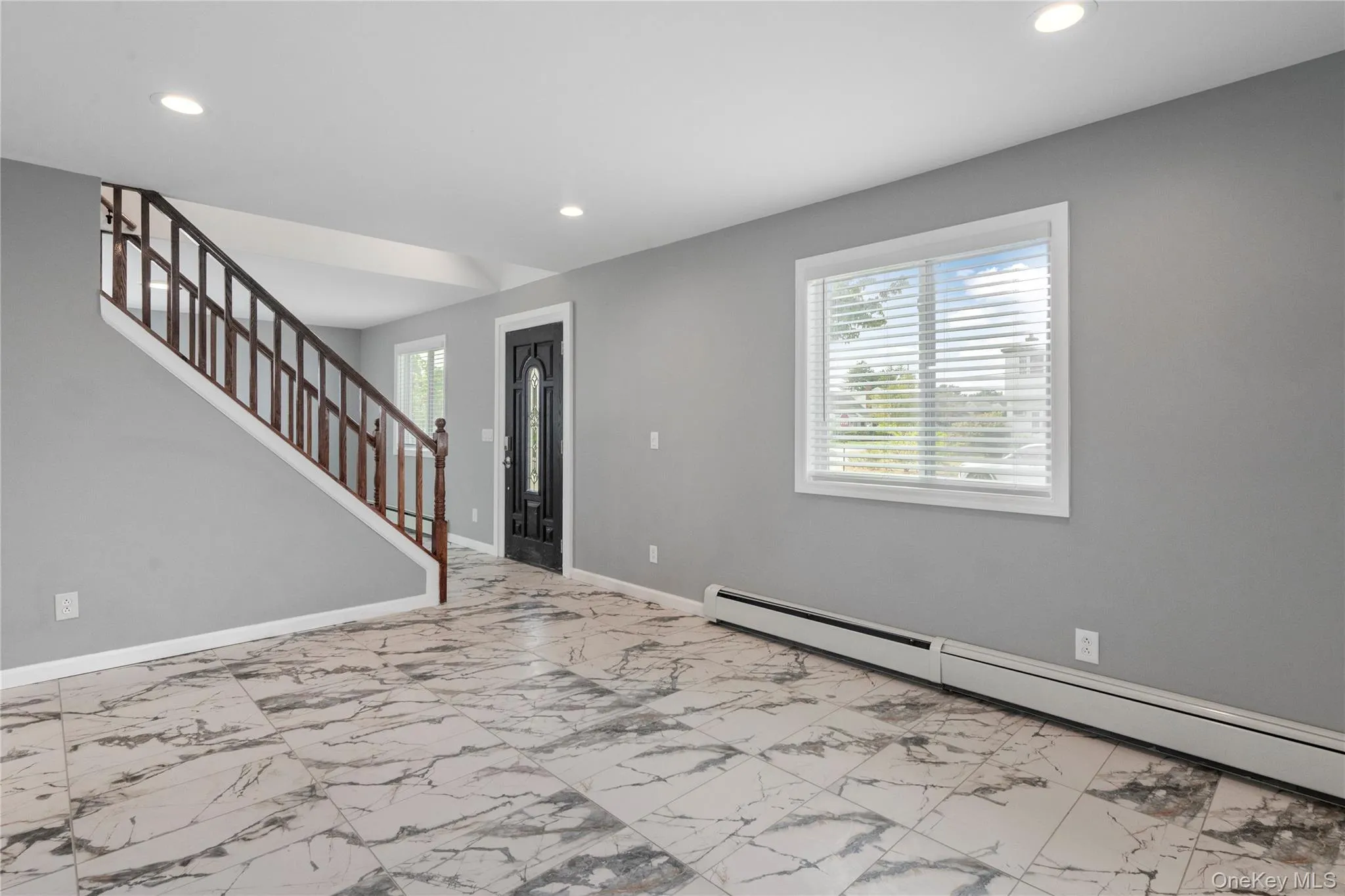 Entryway featuring a baseboard radiator, recessed lighting, light marble finish floors, and stairs Entryway featuring a baseboard radiator, recessed lighting, light marble finish floors, and stairs