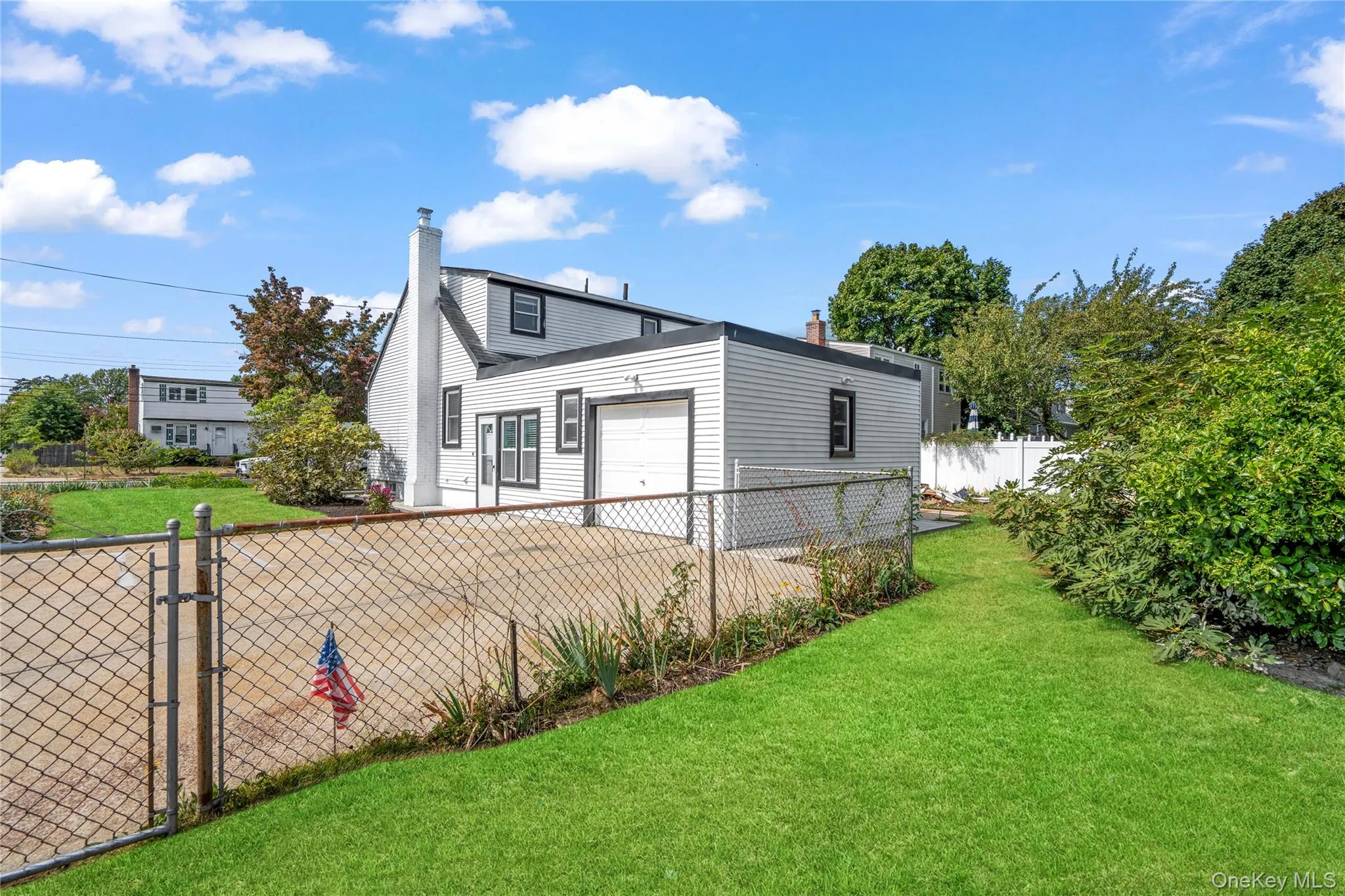 View of property exterior featuring a chimney, driveway, and a garage View of property exterior featuring a chimney, driveway, and a garage