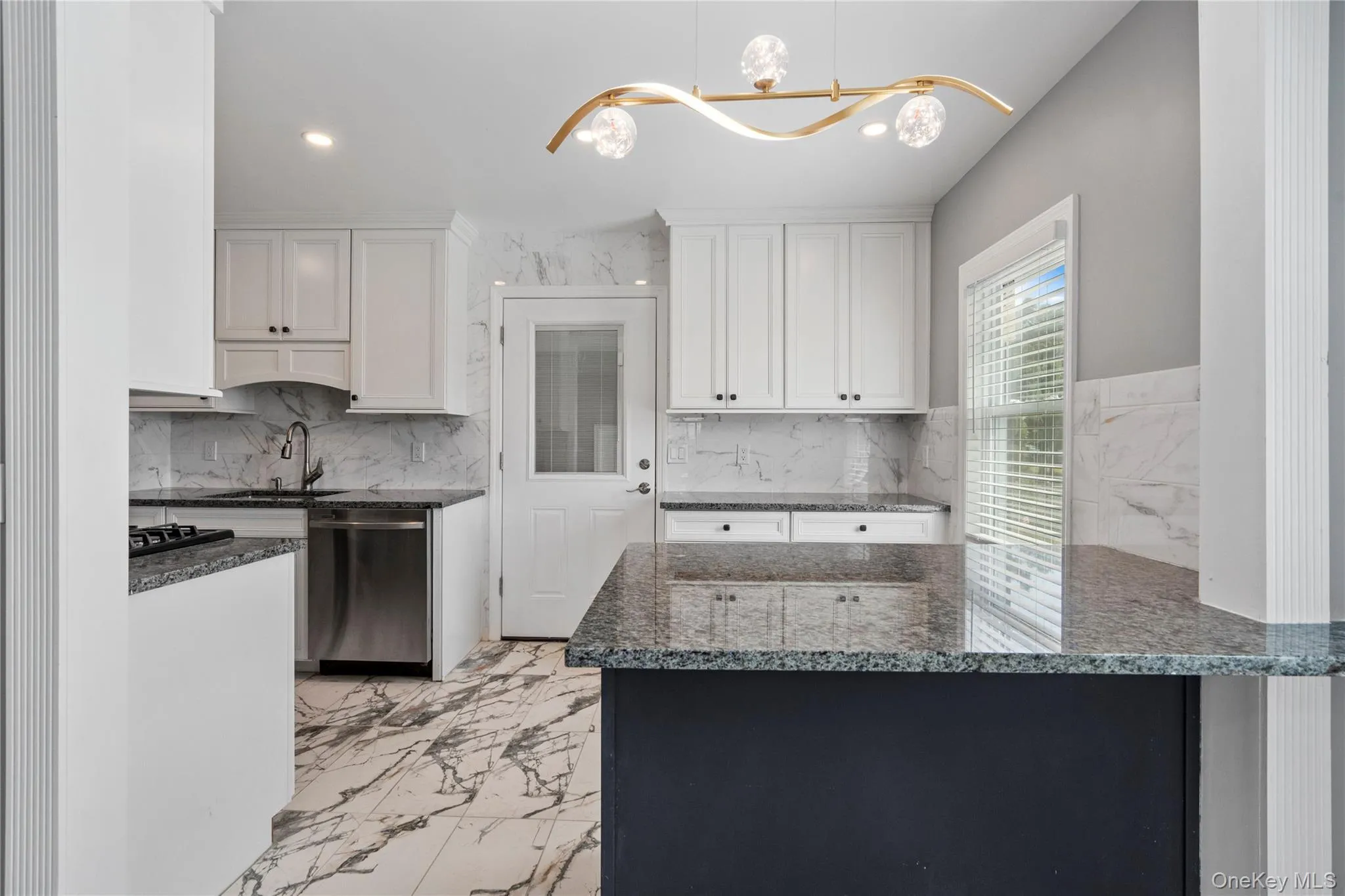 Kitchen with light marble finish floors, dark stone countertops, dishwasher, white cabinets, and recessed lighting Kitchen with light marble finish floors, dark stone countertops, dishwasher, white cabinets, and recessed lighting