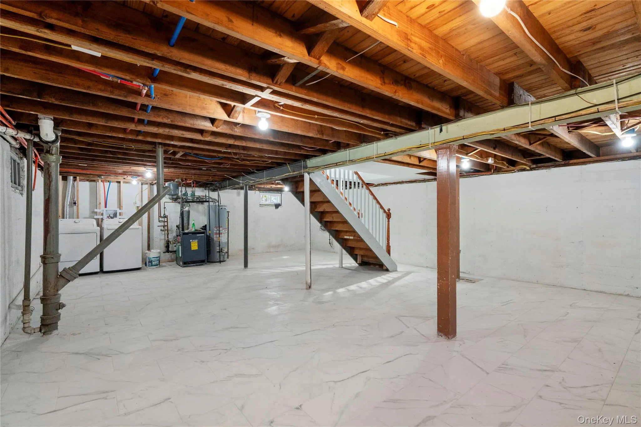 Unfinished basement with stairway, washer and clothes dryer, water heater, and a heating unit Unfinished basement with stairway, washer and clothes dryer, water heater, and a heating unit