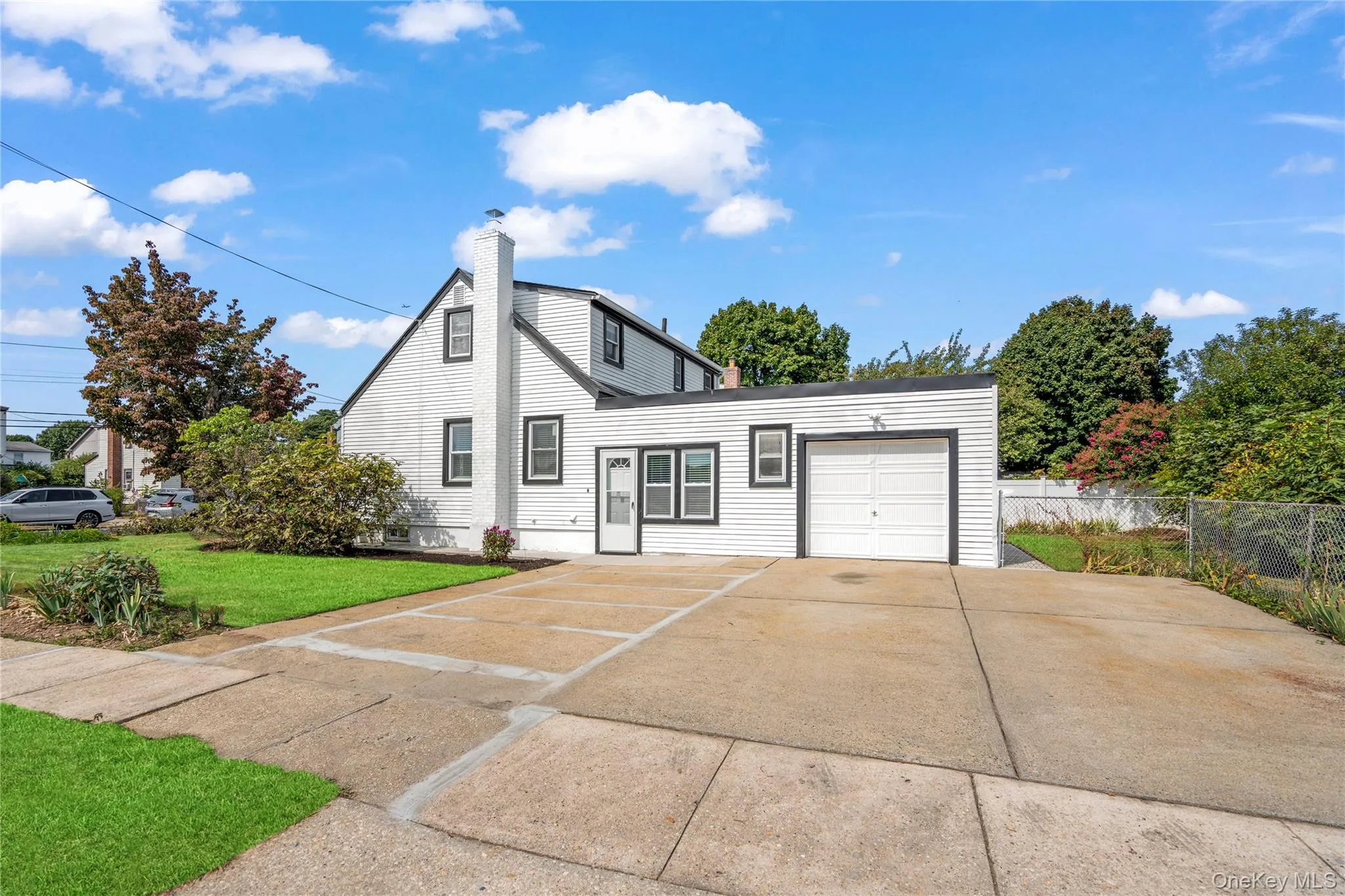 View of front facade featuring driveway, a chimney, and a garage View of front facade featuring driveway, a chimney, and a garage