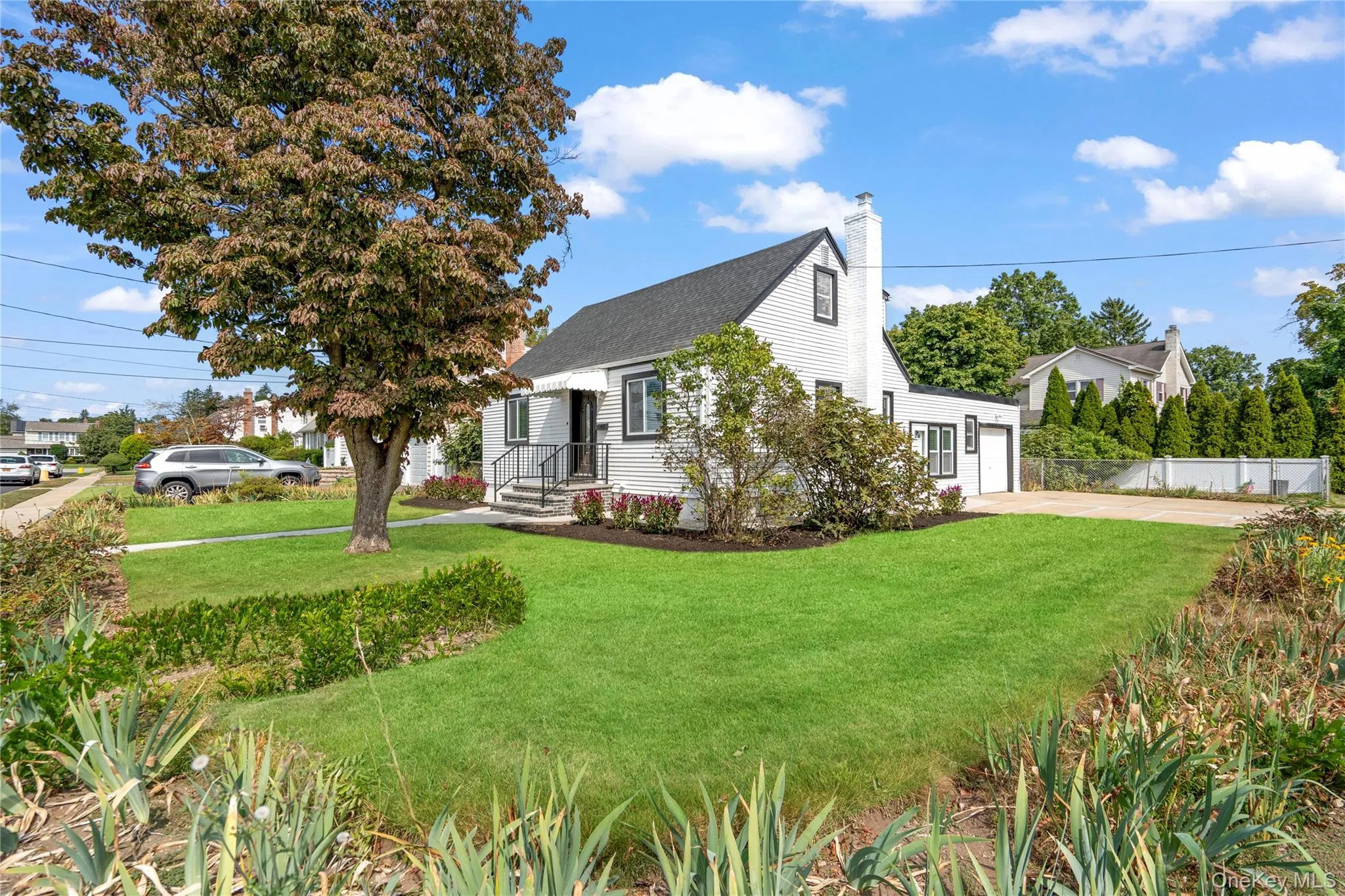 View of front facade with a garage, a chimney, roof with shingles, and concrete driveway View of front facade with a garage, a chimney, roof with shingles, and concrete driveway
