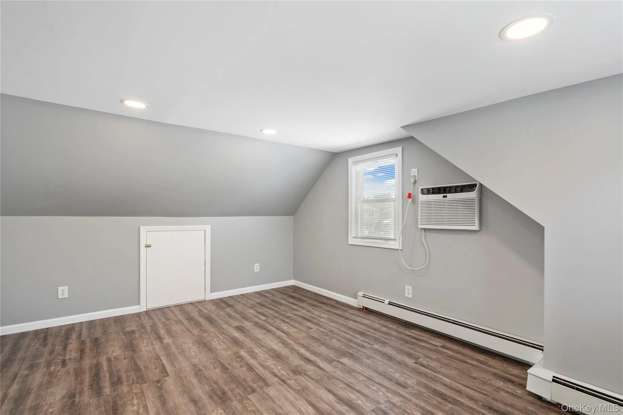 Bonus room featuring lofted ceiling, a baseboard radiator, wood finished floors, recessed lighting, and an AC wall unit Bonus room featuring lofted ceiling, a baseboard radiator, wood finished floors, recessed lighting, and an AC wall unit