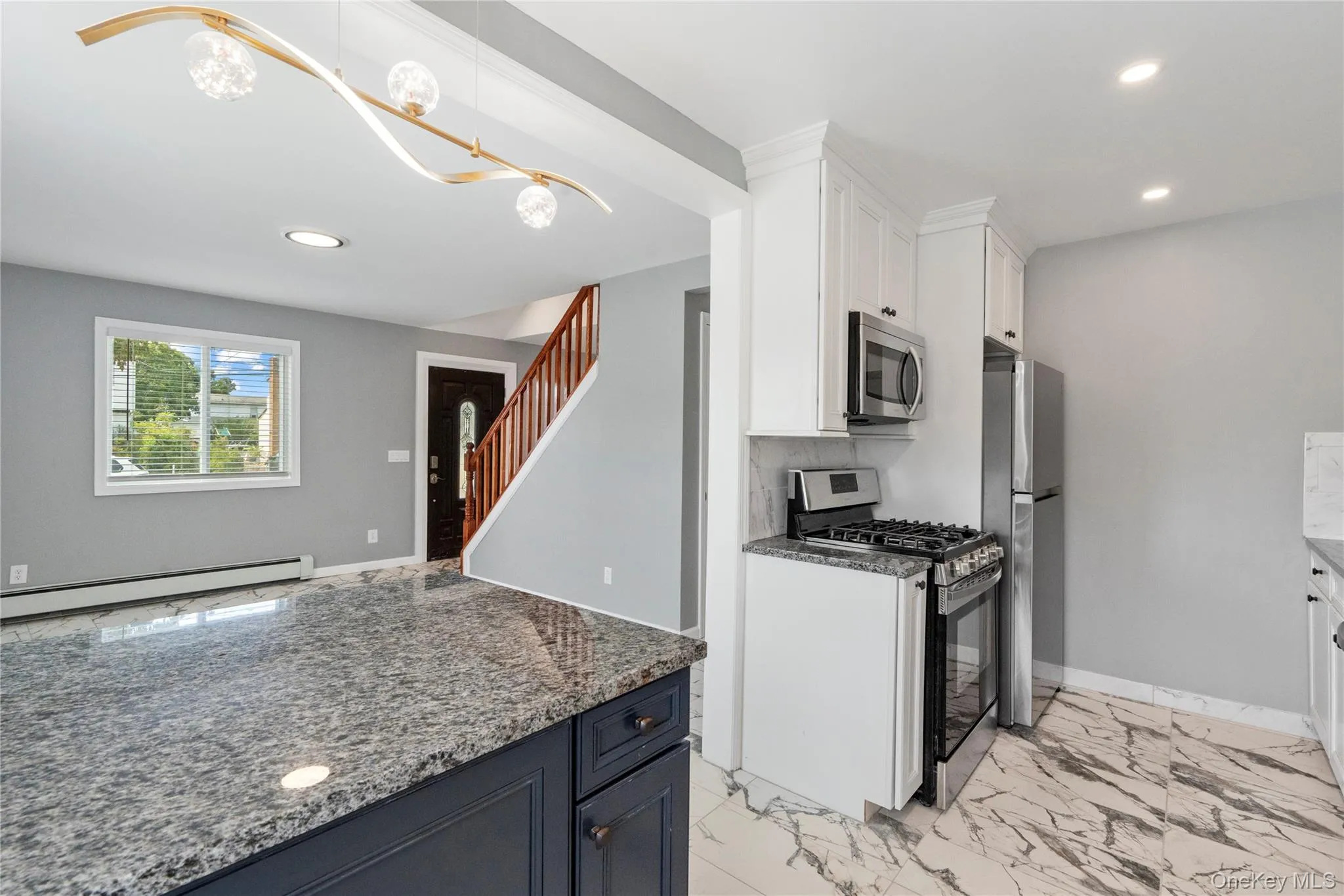 Kitchen with white cabinets, stainless steel appliances, dark stone counters, recessed lighting, and light marble finish floors Kitchen with white cabinets, stainless steel appliances, dark stone counters, recessed lighting, and light marble finish floors