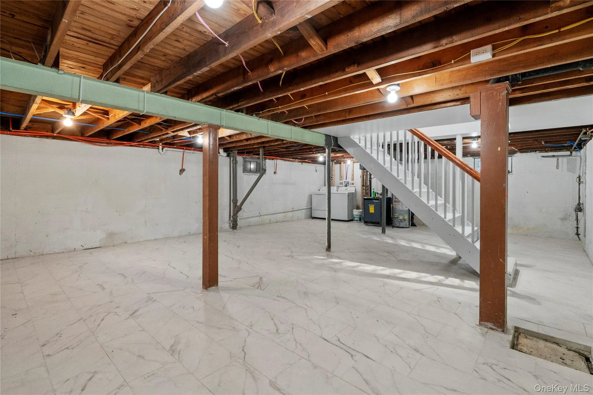 Unfinished basement with stairs, washing machine and clothes dryer, and marble look tile flooring Unfinished basement with stairs, washing machine and clothes dryer, and marble look tile flooring