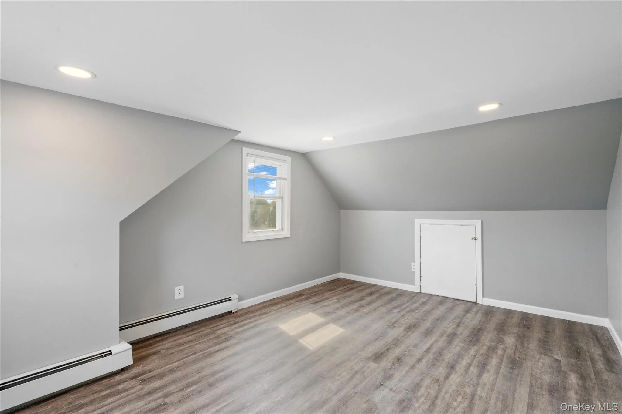 Bonus room with a baseboard radiator, recessed lighting, lofted ceiling, and wood finished floors Bonus room with a baseboard radiator, recessed lighting, lofted ceiling, and wood finished floors