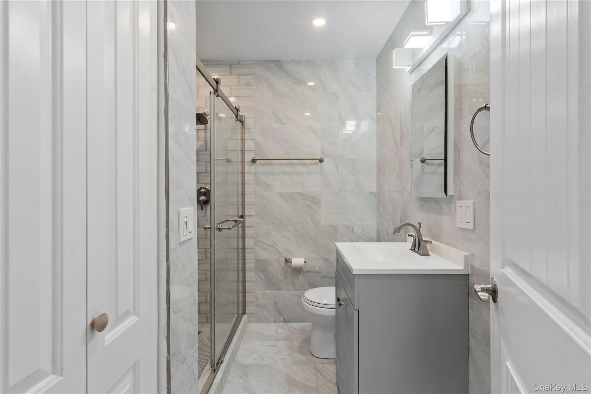 Full bath featuring tile walls, vanity, a stall shower, and recessed lighting Full bath featuring tile walls, vanity, a stall shower, and recessed lighting