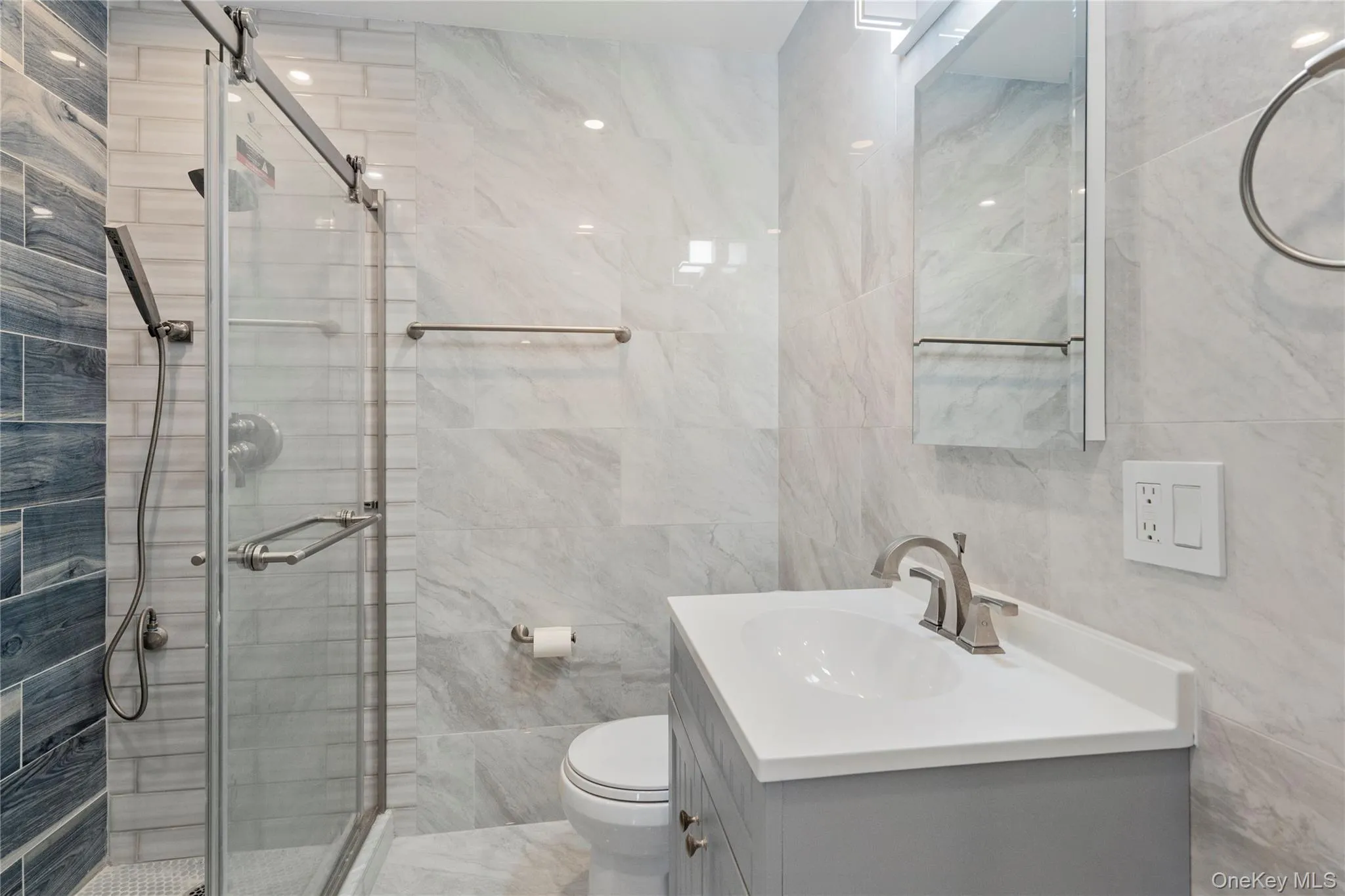 Bathroom featuring tile walls, vanity, and a stall shower Bathroom featuring tile walls, vanity, and a stall shower
