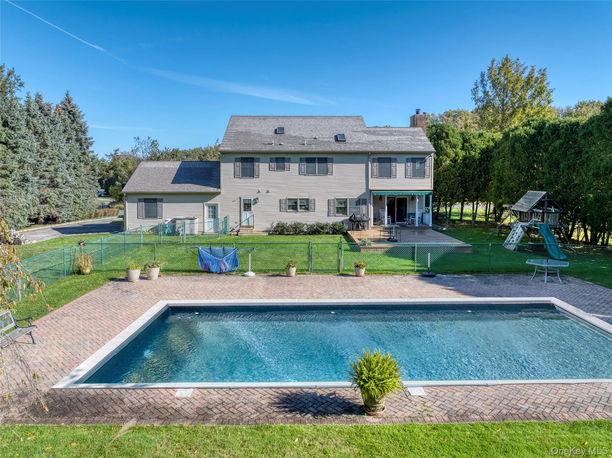 Rear view of house with a patio area, a playground, a chimney, and a fenced backyard Rear view of house with a patio area, a playground, a chimney, and a fenced backyard