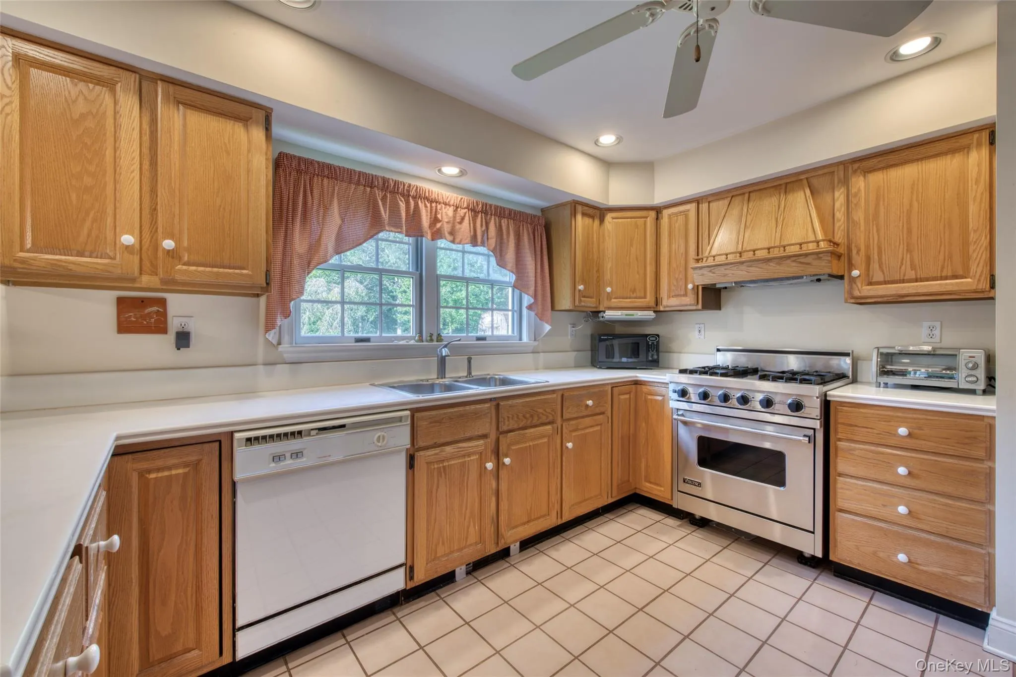 Kitchen featuring luxury range, premium range hood, recessed lighting, light countertops, and white dishwasher Kitchen featuring luxury range, premium range hood, recessed lighting, light countertops, and white dishwasher