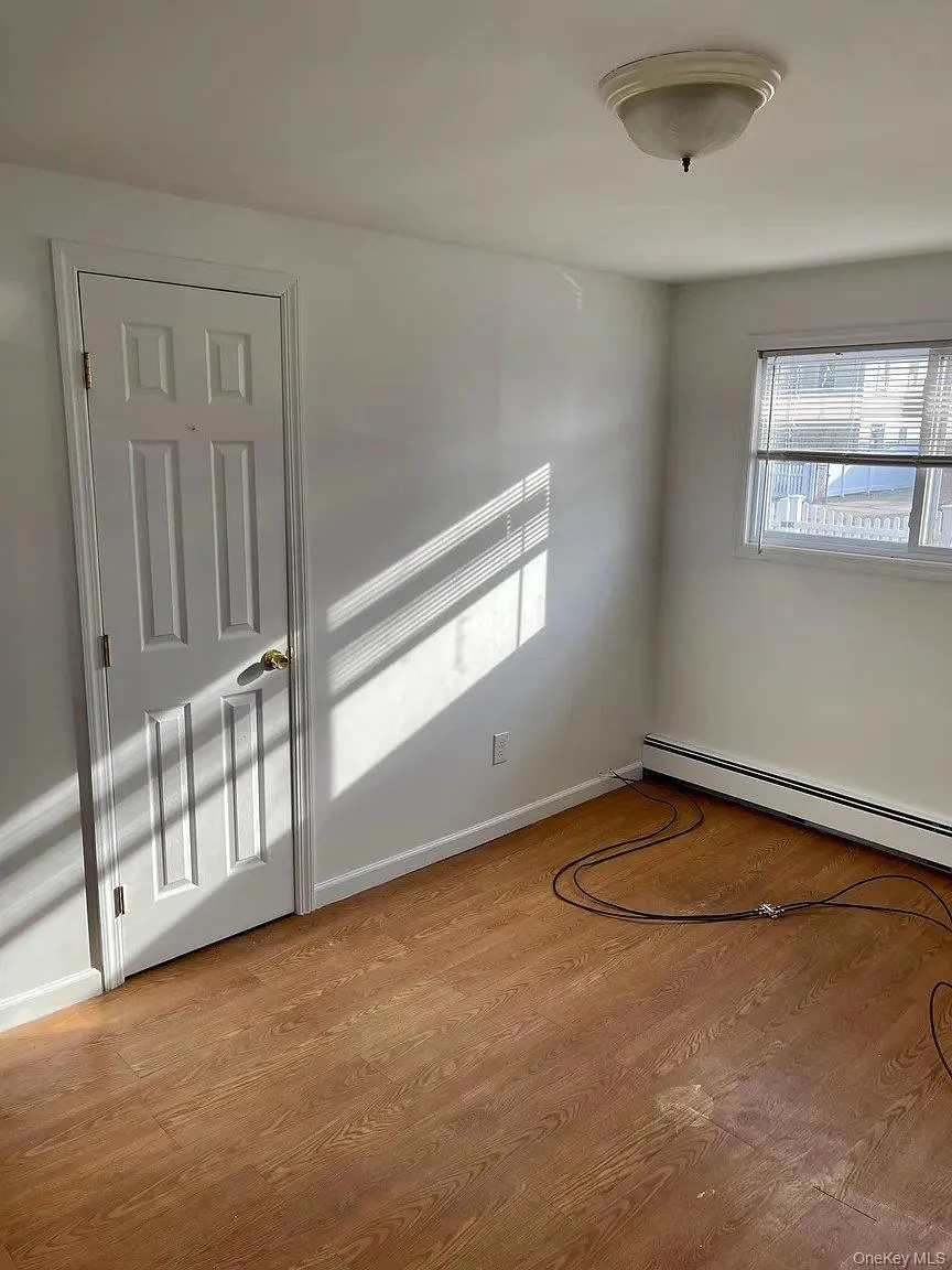 Empty room featuring baseboard heating and light wood-style flooring Empty room featuring baseboard heating and light wood-style flooring