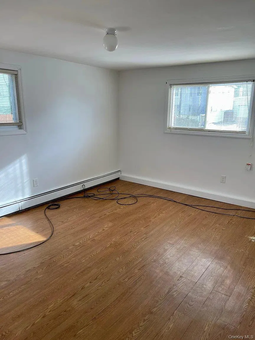 Spare room with baseboard heating and wood finished floors Spare room with baseboard heating and wood finished floors