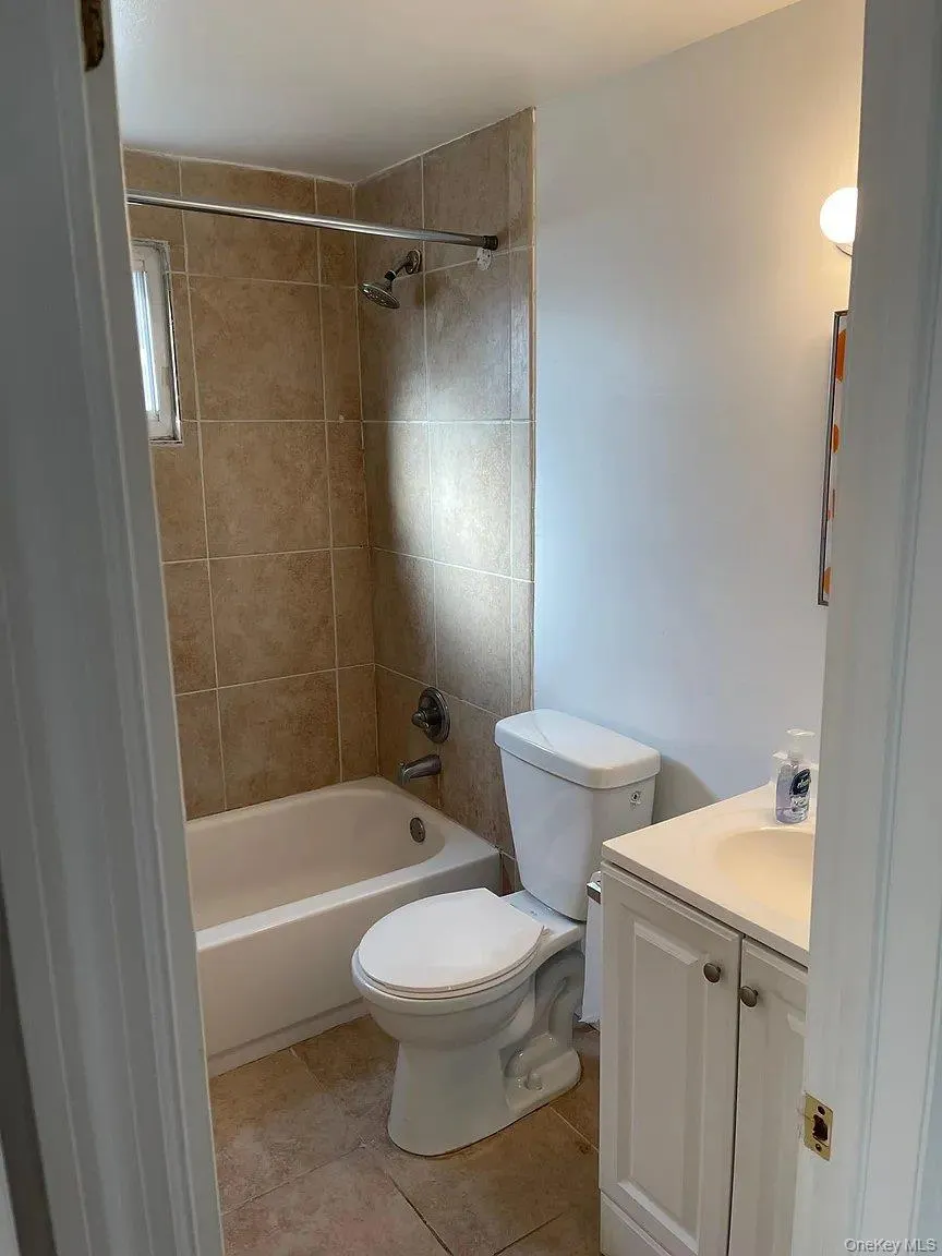 Bathroom with vanity, washtub / shower combination, and light tile patterned floors Bathroom with vanity, washtub / shower combination, and light tile patterned floors