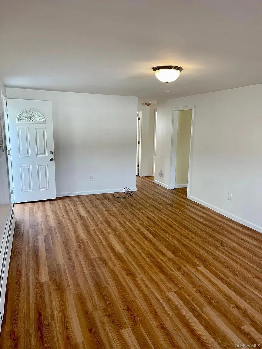 Unfurnished room with light wood finished floors and a baseboard heating unit Unfurnished room with light wood finished floors and a baseboard heating unit