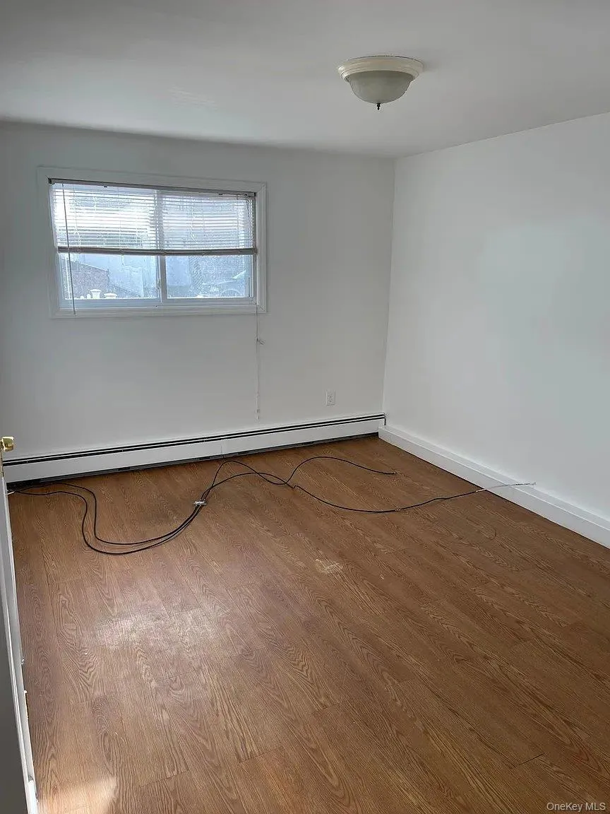 Empty room featuring a baseboard heating unit and wood finished floors Empty room featuring a baseboard heating unit and wood finished floors