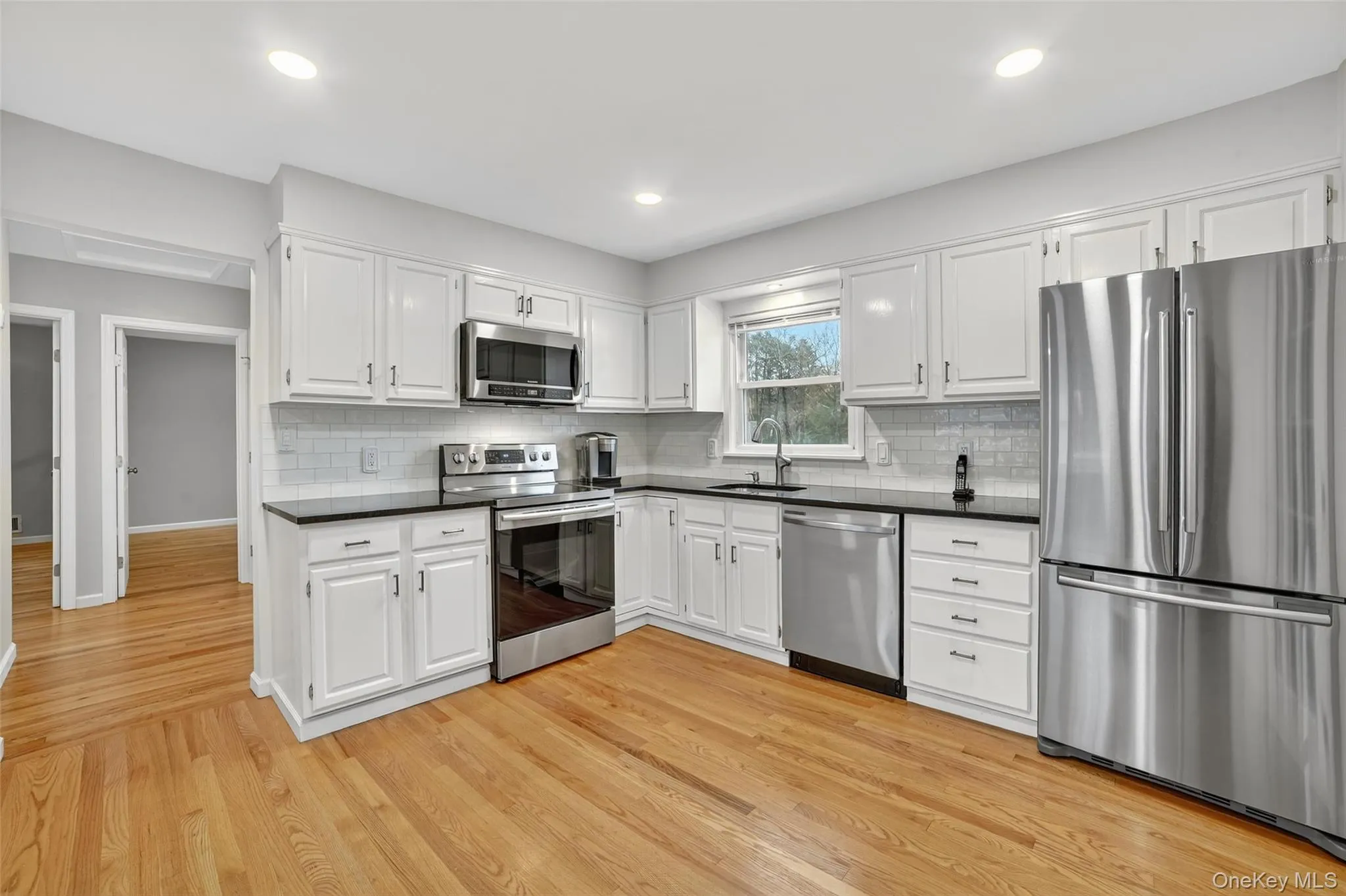 Kitchen featuring stainless steel appliances, white cabinets, light wood finished floors, tasteful backsplash, and recessed lighting Kitchen featuring stainless steel appliances, white cabinets, light wood finished floors, tasteful backsplash, and recessed lighting