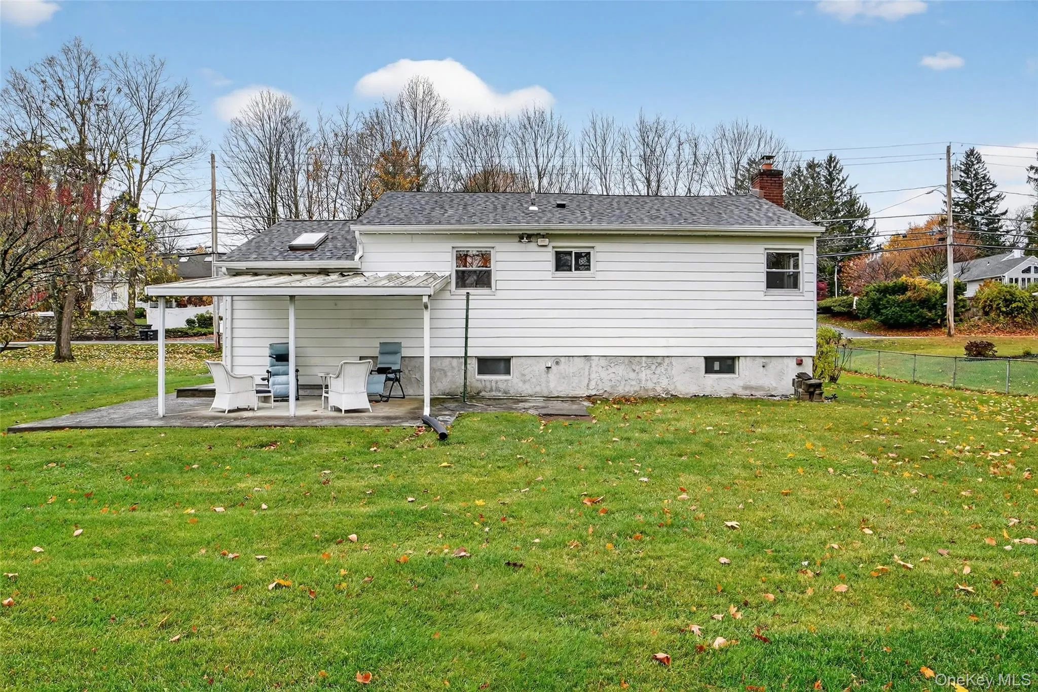 Rear view of house featuring a patio, a chimney, and a shingled roof Rear view of house featuring a patio, a chimney, and a shingled roof
