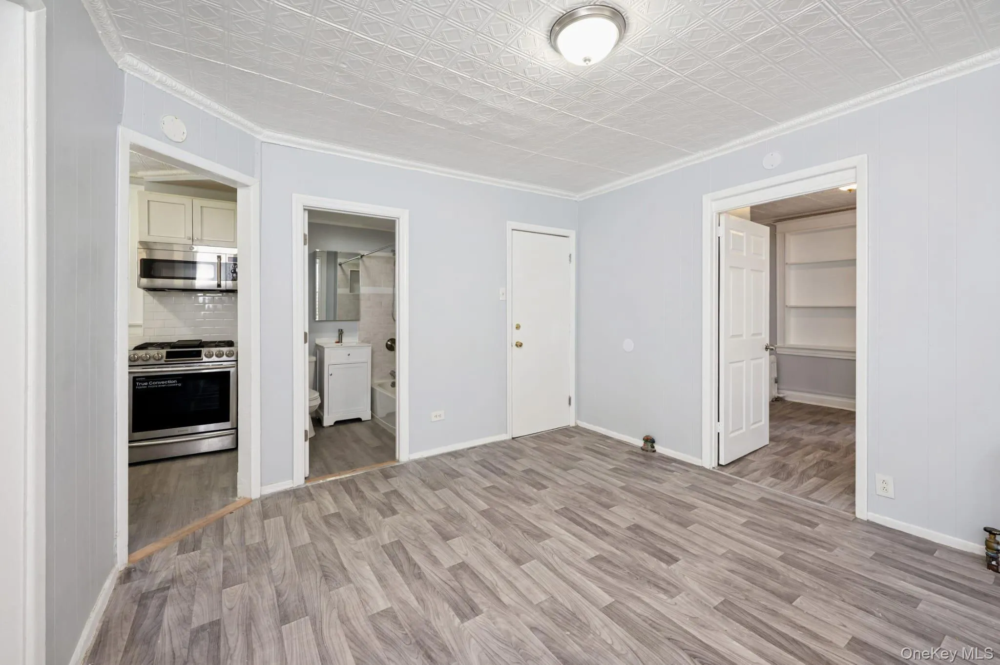 Unfurnished bedroom with ornamental molding, light wood-type flooring, a walk in closet, an ornate ceiling, and ensuite bathroom Unfurnished bedroom with ornamental molding, light wood-type flooring, a walk in closet, an ornate ceiling, and ensuite bathroom