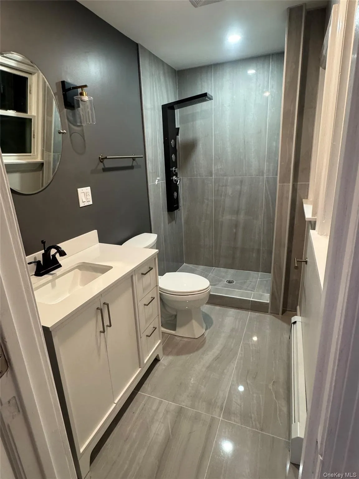 Bathroom with vanity, a stall shower, and a baseboard heating unit Bathroom with vanity, a stall shower, and a baseboard heating unit