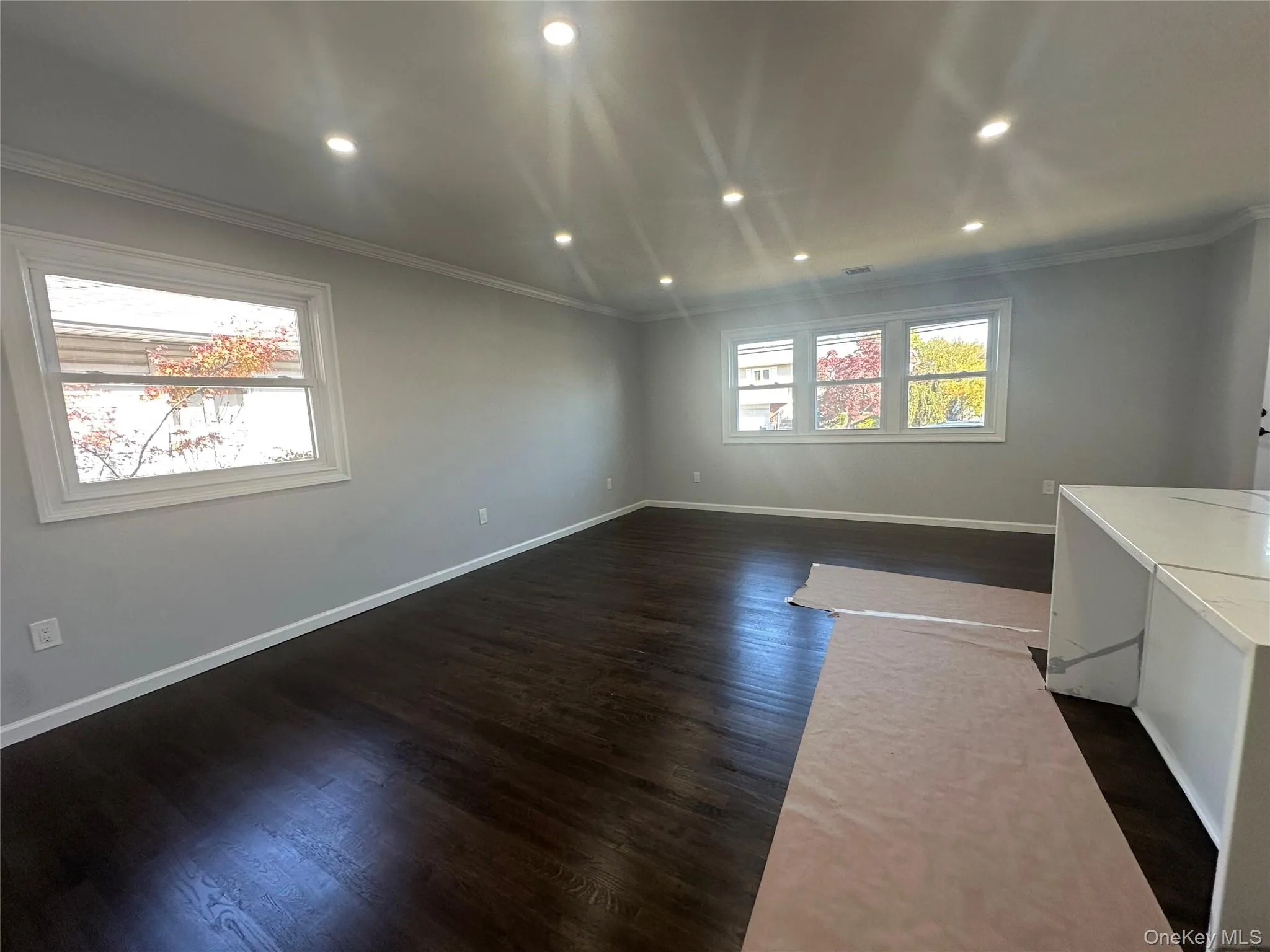 Empty room featuring recessed lighting, dark wood finished floors, and ornamental molding Empty room featuring recessed lighting, dark wood finished floors, and ornamental molding