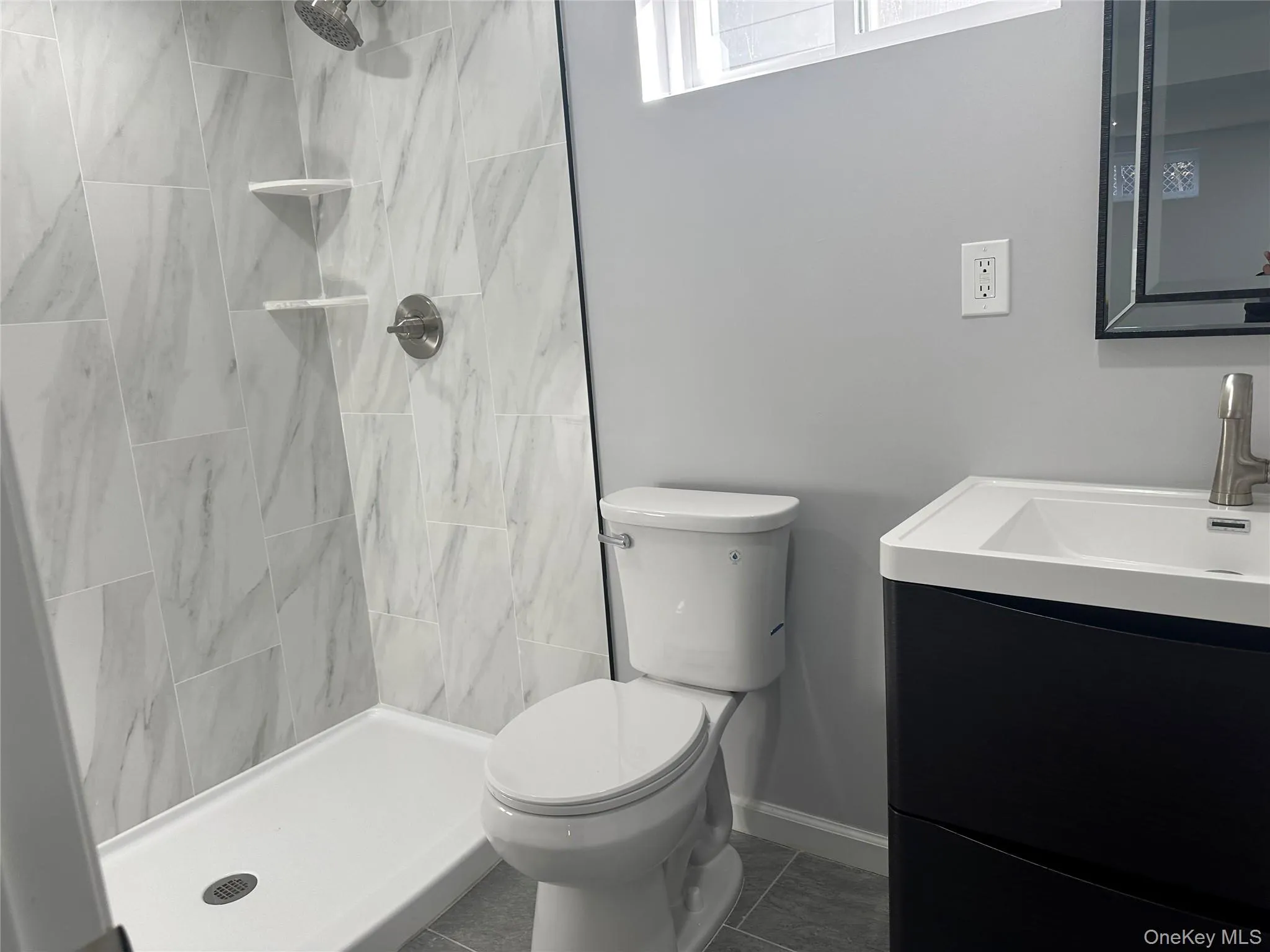 Bathroom featuring vanity, a shower stall, and dark tile patterned floors Bathroom featuring vanity, a shower stall, and dark tile patterned floors
