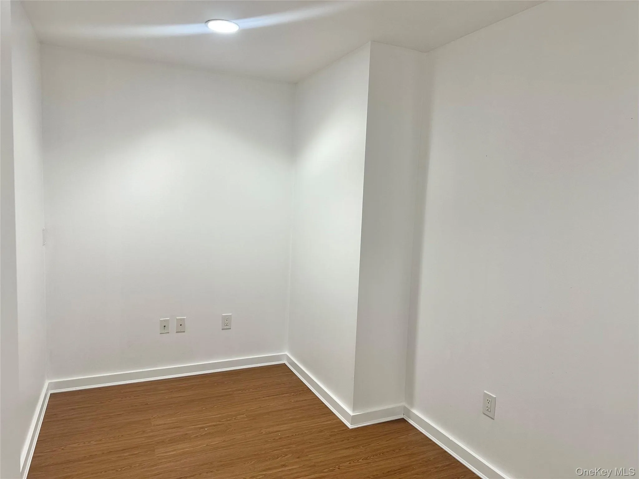 Spare room with dark wood-style floors and baseboards Spare room with dark wood-style floors and baseboards
