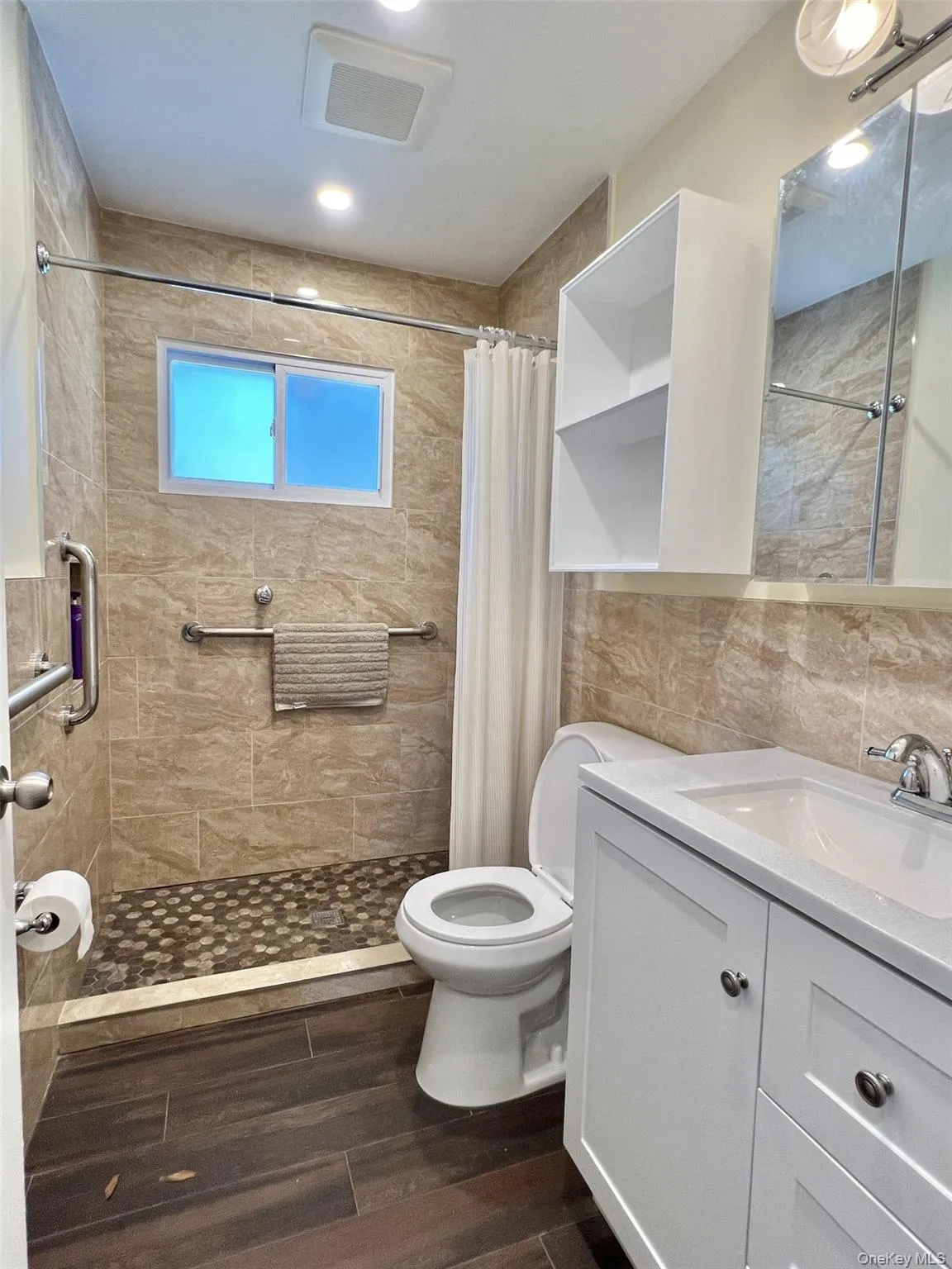 Bathroom with vanity, a shower stall, dark wood-type flooring, and tile walls Bathroom with vanity, a shower stall, dark wood-type flooring, and tile walls