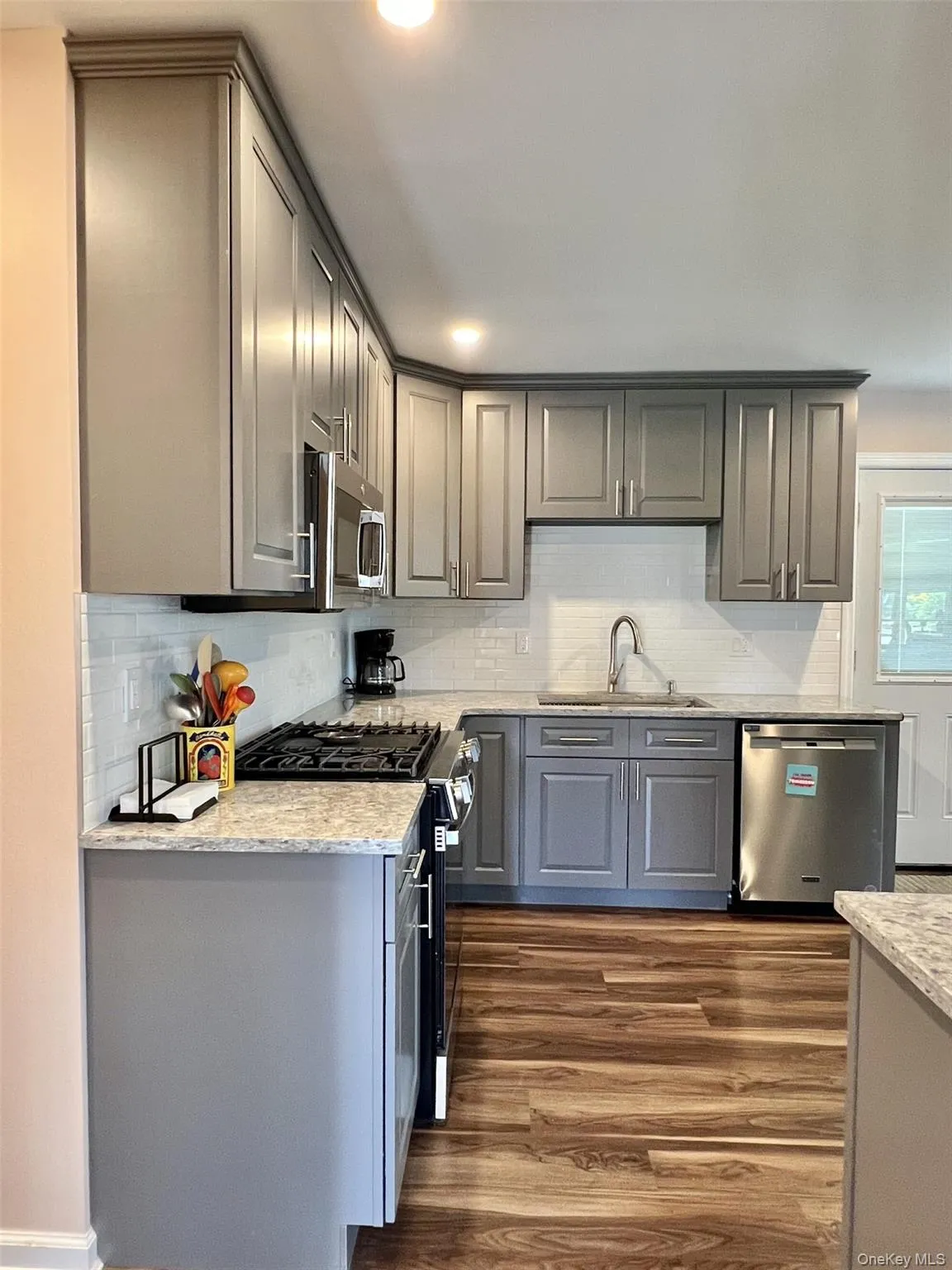Kitchen featuring gray cabinets, light stone countertops, stainless steel appliances, backsplash, and recessed lighting Kitchen featuring gray cabinets, light stone countertops, stainless steel appliances, backsplash, and recessed lighting
