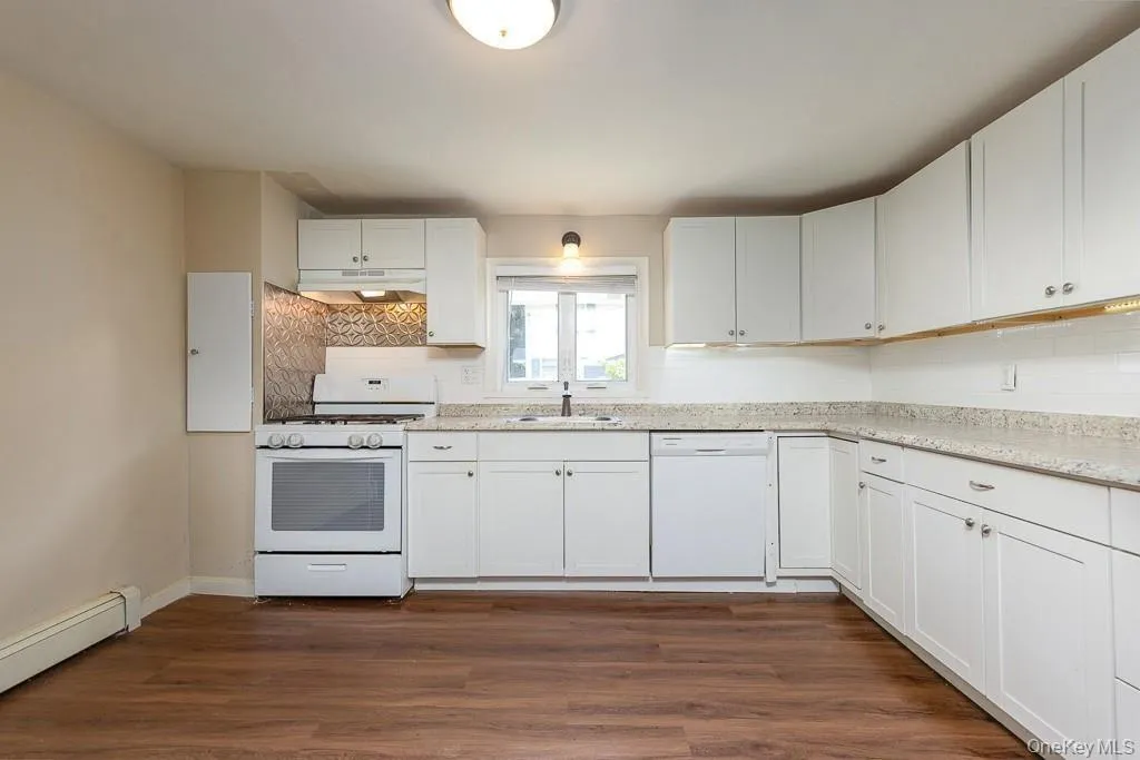 Kitchen with white appliances, white cabinets, dark wood-type flooring, and decorative backsplash Kitchen with white appliances, white cabinets, dark wood-type flooring, and decorative backsplash