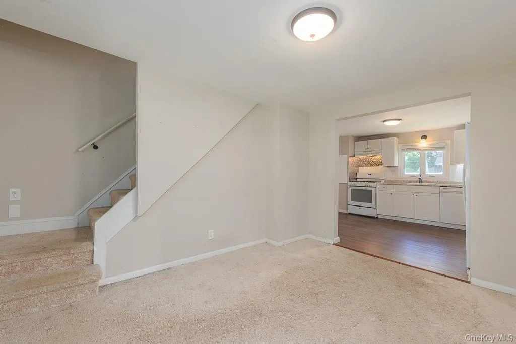 Unfurnished living room featuring light carpet and stairs Unfurnished living room featuring light carpet and stairs