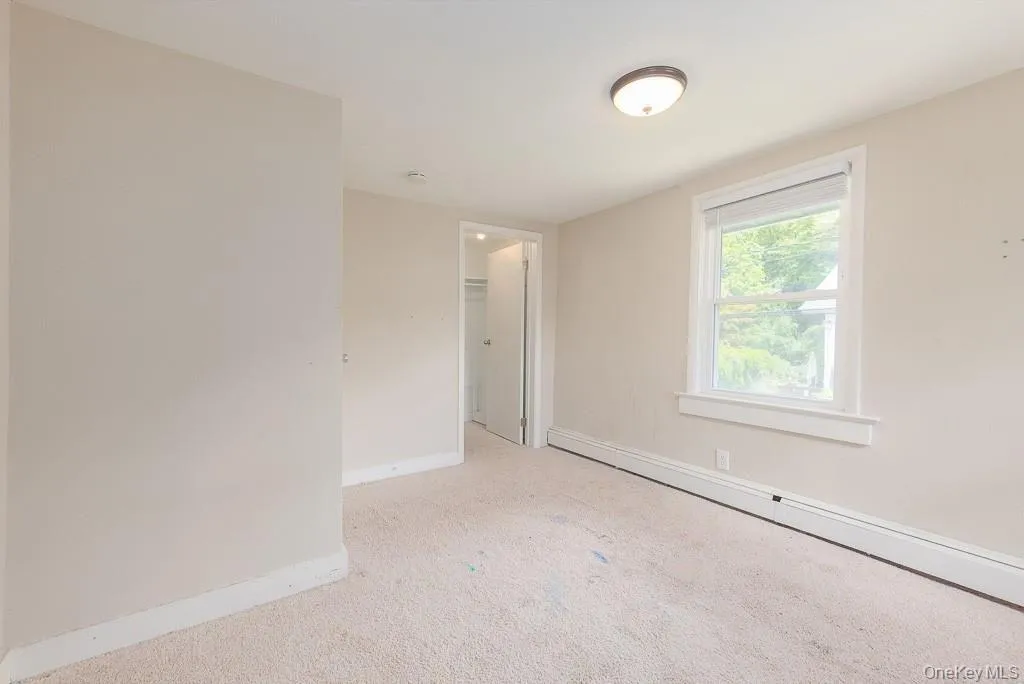 Empty room featuring a baseboard radiator and light colored carpet Empty room featuring a baseboard radiator and light colored carpet