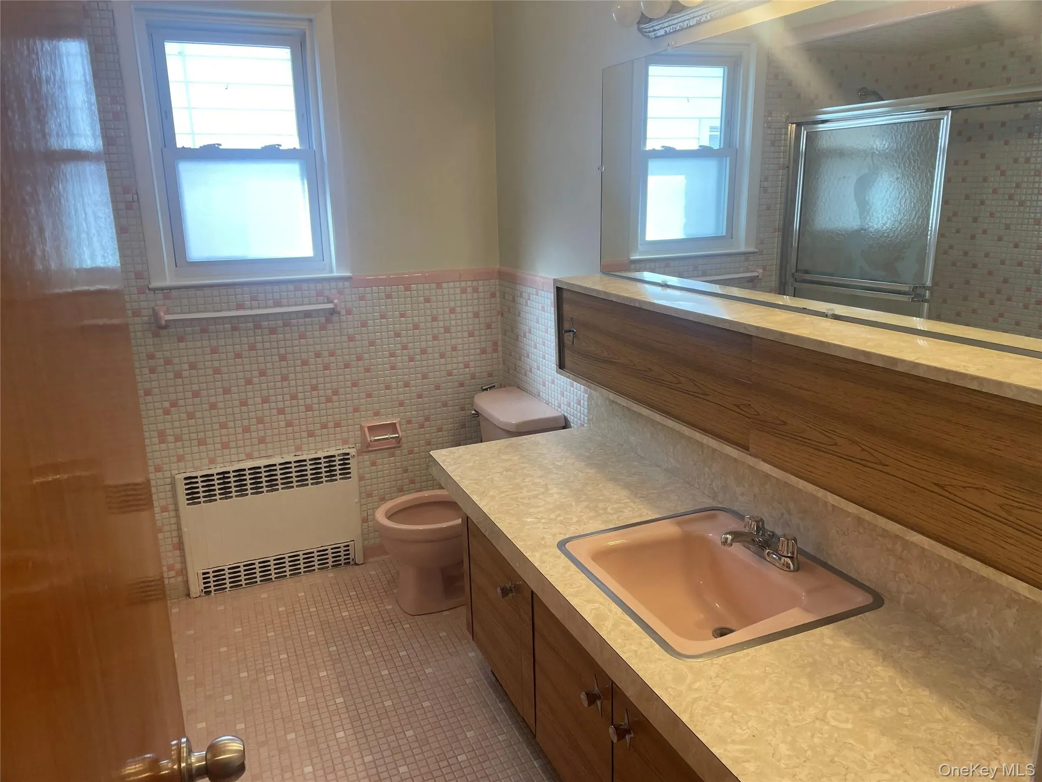 Full bathroom featuring vanity, tile walls, a wainscoted wall, radiator heating unit, and light tile patterned flooring Full bathroom featuring vanity, tile walls, a wainscoted wall, radiator heating unit, and light tile patterned flooring