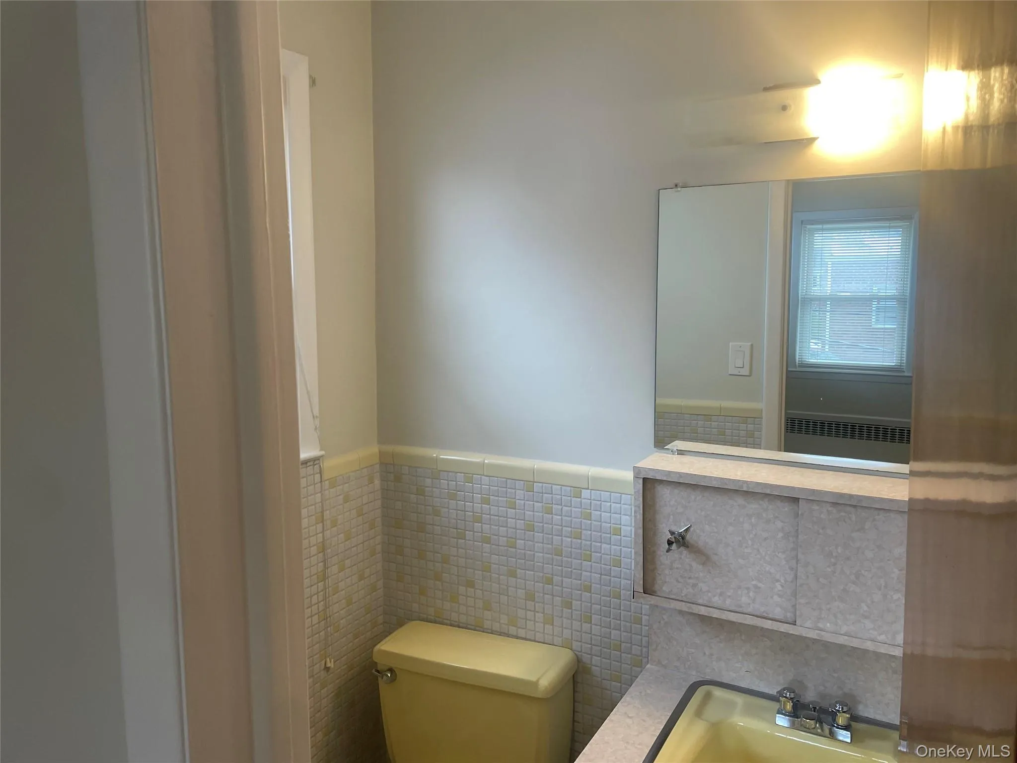 Bathroom with tile walls, a wainscoted wall, radiator heating unit, and vanity Bathroom with tile walls, a wainscoted wall, radiator heating unit, and vanity