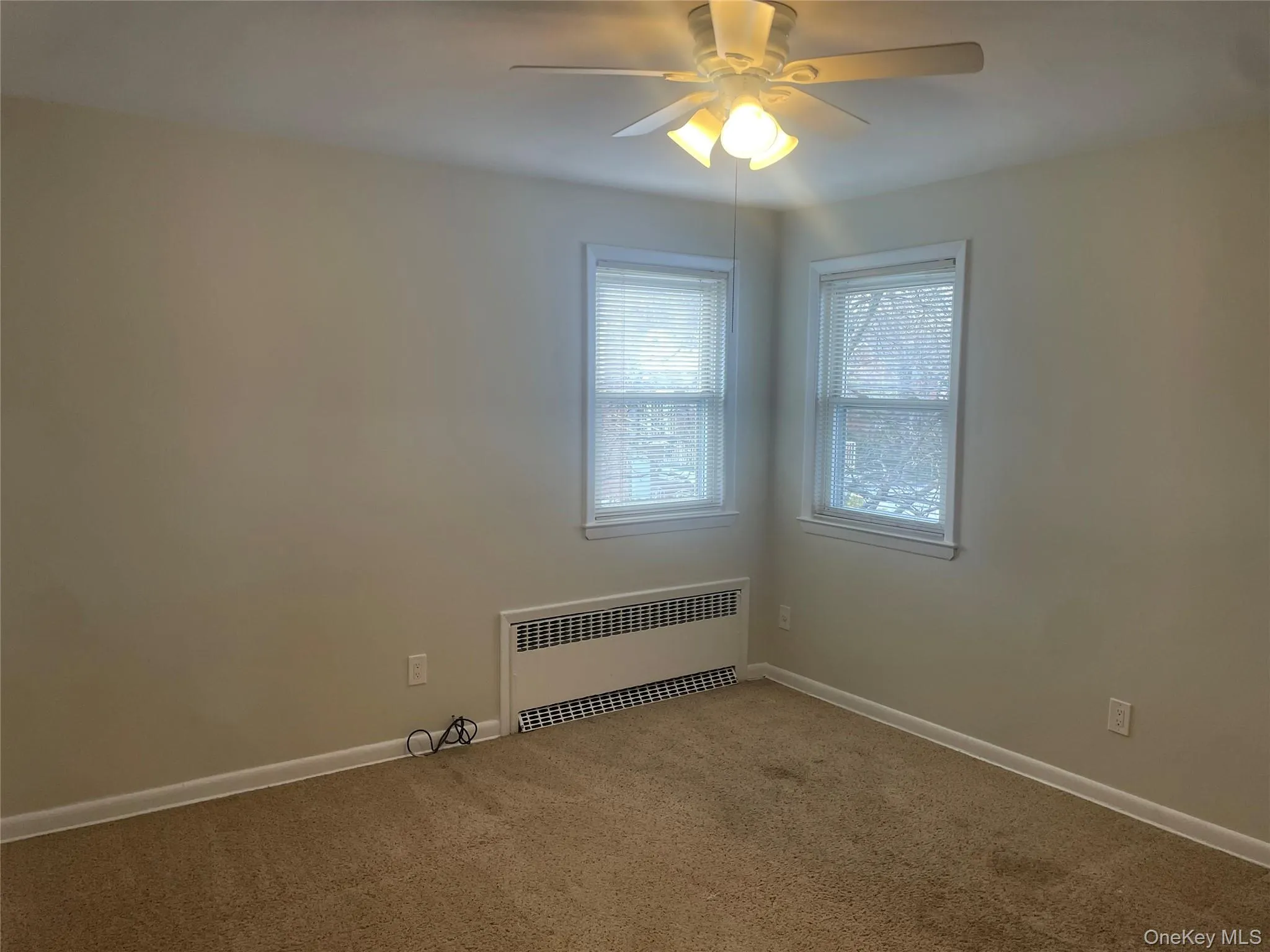 Carpeted spare room with radiator and ceiling fan Carpeted spare room with radiator and ceiling fan