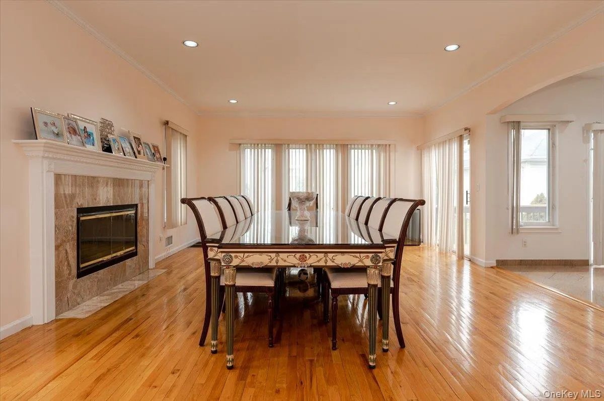 Dining area with crown molding, arched walkways, light wood finished floors, a fireplace, and recessed lighting Dining area with crown molding, arched walkways, light wood finished floors, a fireplace, and recessed lighting