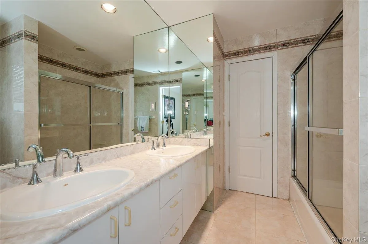 Bathroom featuring light tile patterned floors, double vanity, recessed lighting, and tile walls Bathroom featuring light tile patterned floors, double vanity, recessed lighting, and tile walls