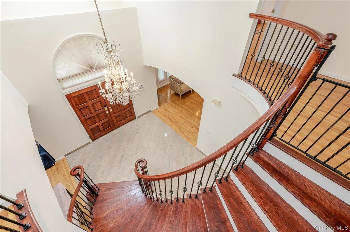 Foyer entrance featuring wood finished floors, a chandelier, a high ceiling, and arched walkways Foyer entrance featuring wood finished floors, a chandelier, a high ceiling, and arched walkways